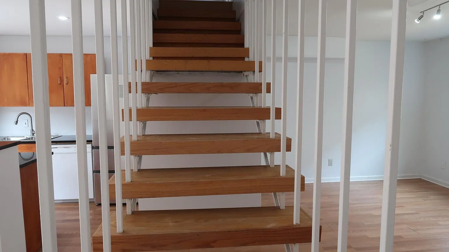 Open-tread staircase featuring wood-finish treads and white vertical railings