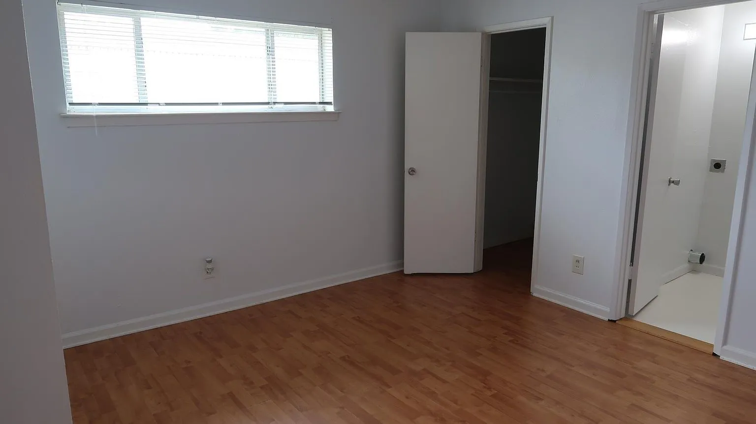 Bedroom with wood-finish flooring and white baseboards