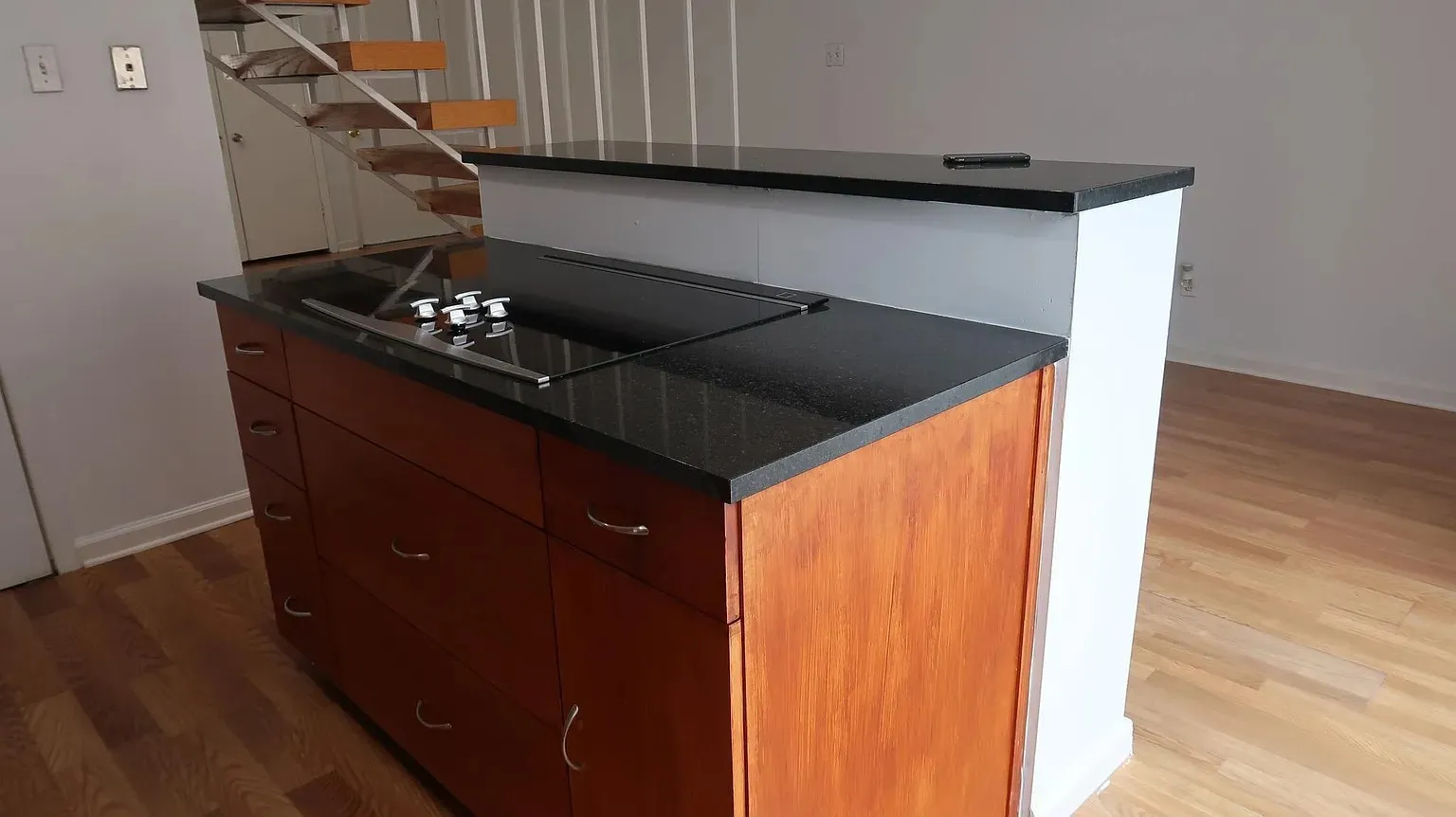 Kitchen island featuring a built-in cooktop and wood-finish cabinetry