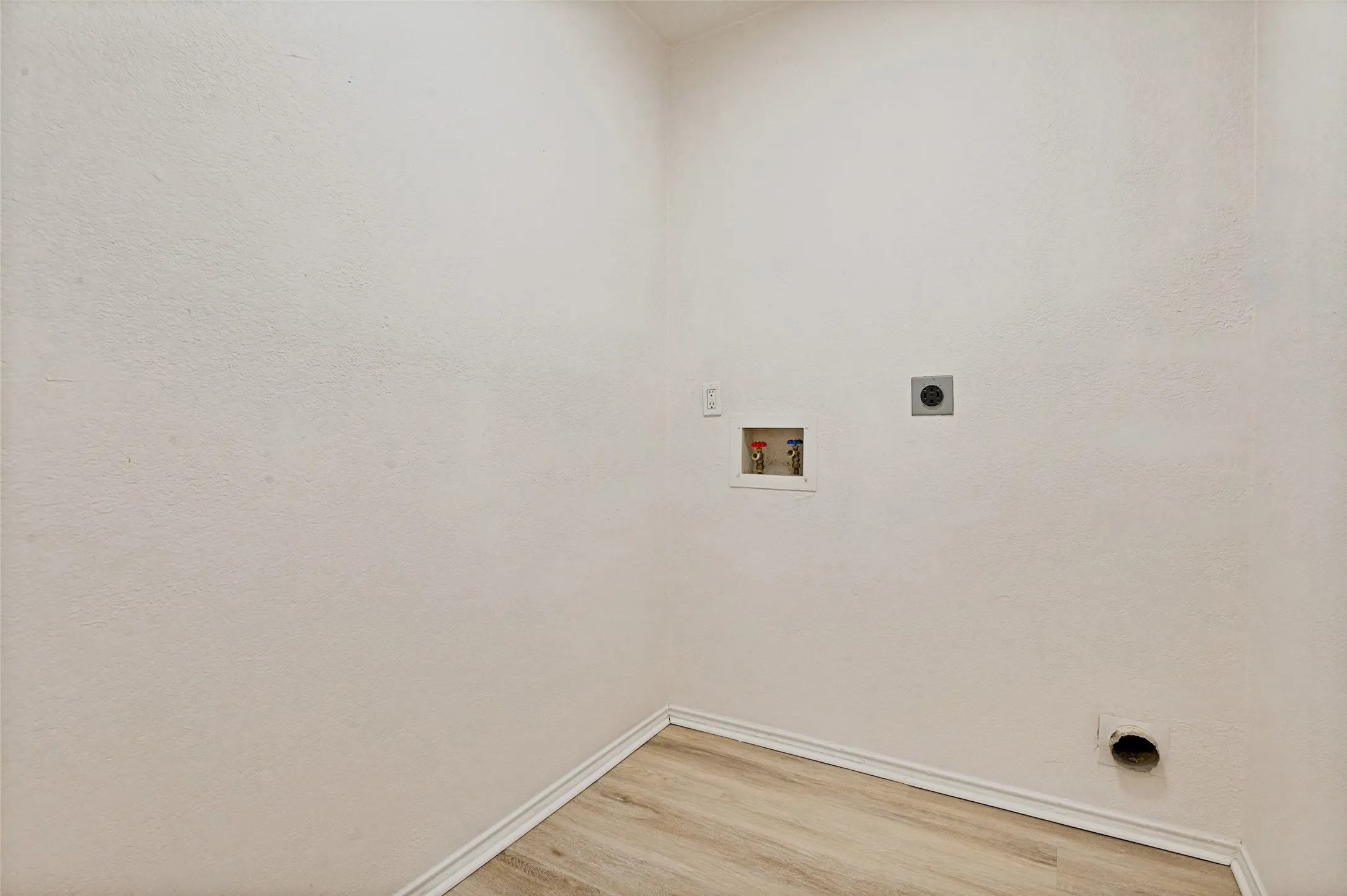 Utility space featuring wood-finish flooring and white baseboards