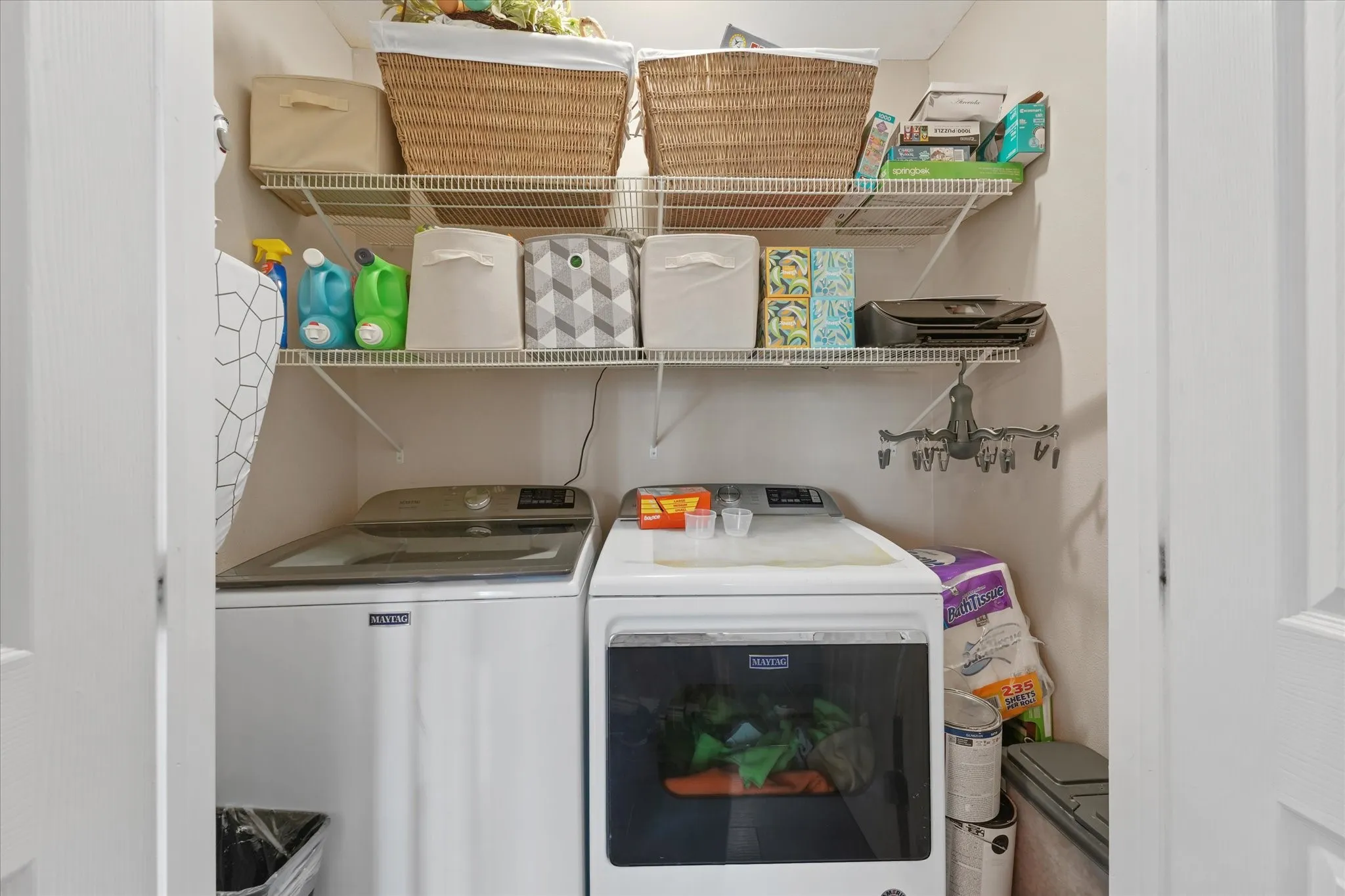 Dedicated laundry closet featuring a top-load washing machine, front-load dryer, and multiple wire shelving units for organization