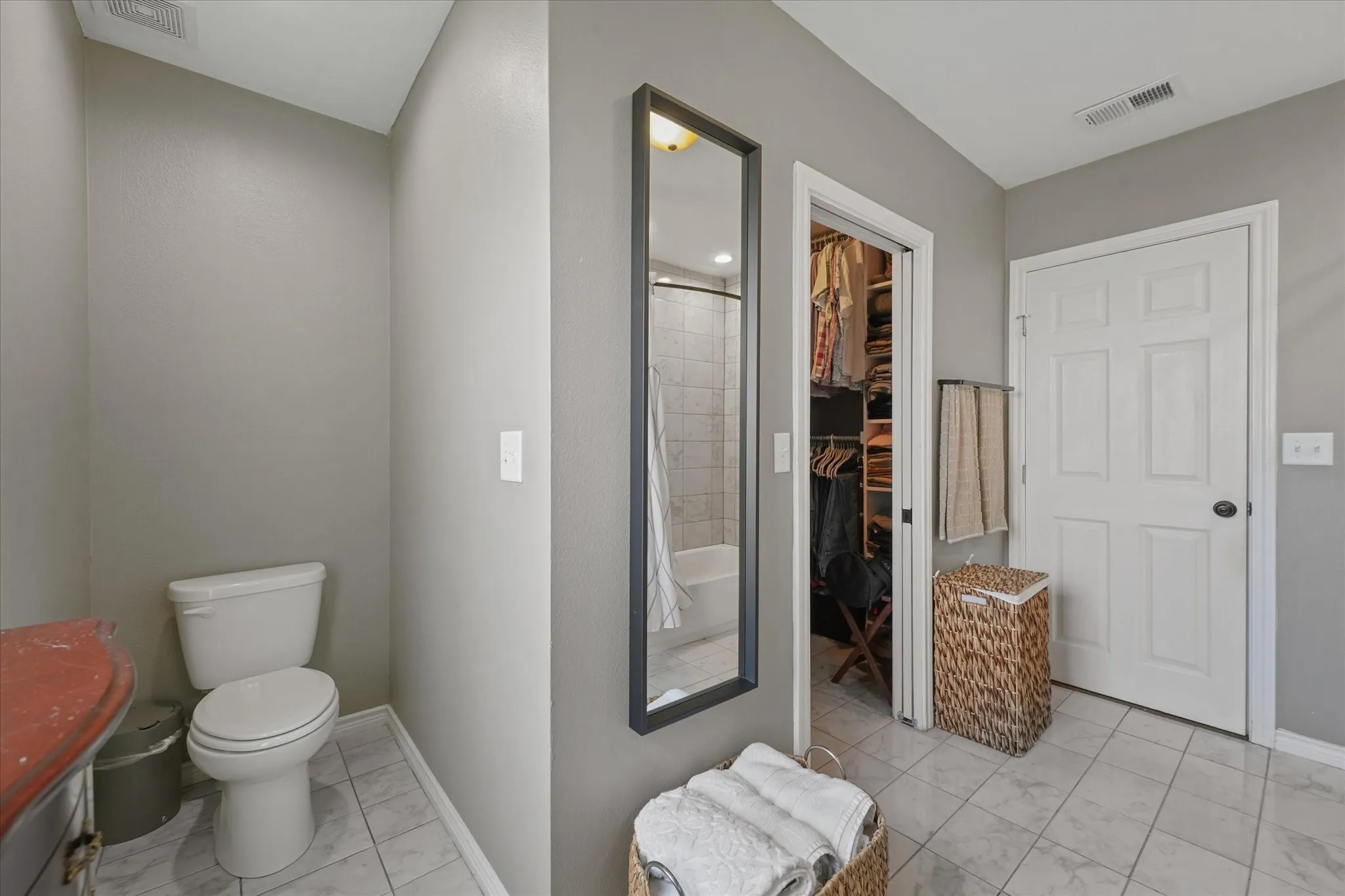 Bathroom featuring tile flooring, a white toilet, and a vanity with a reddish countertop