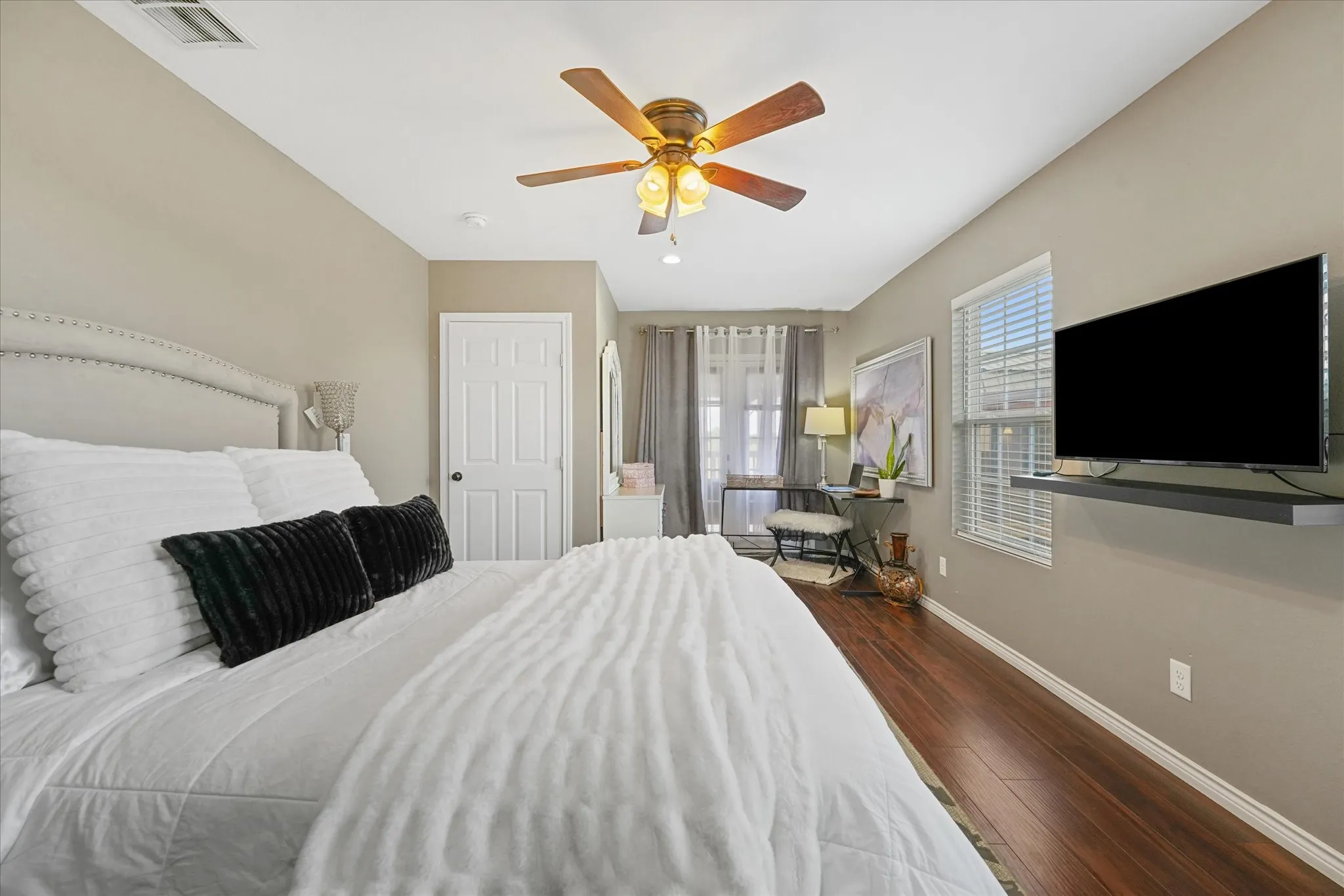 Bedroom featuring wood-finish flooring, a ceiling fan with integrated lighting, and neutral wall tones