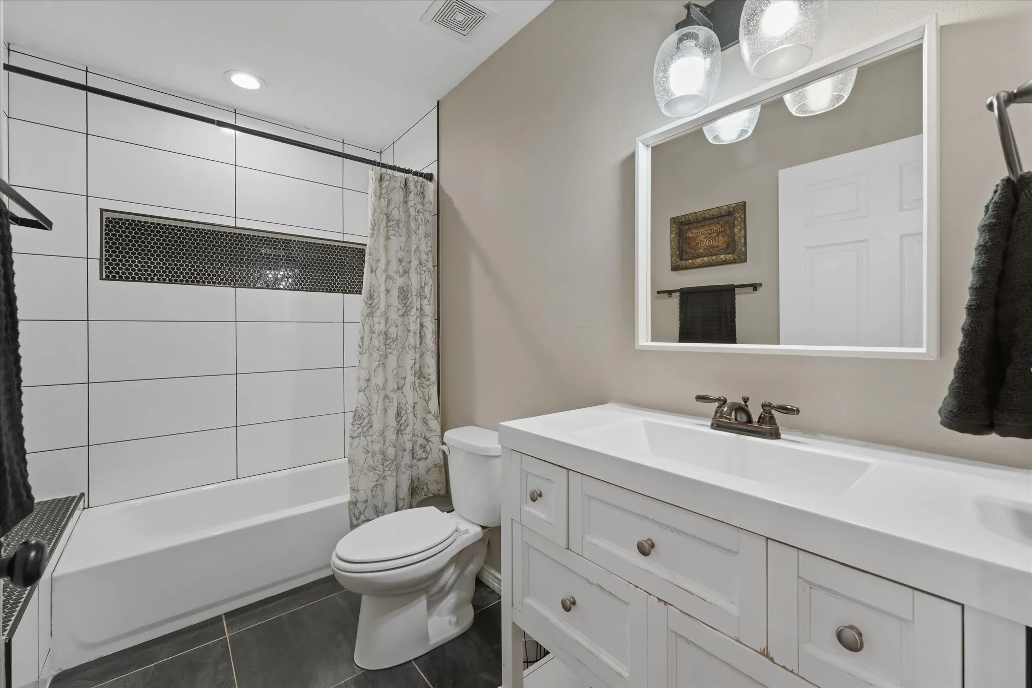 Bathroom featuring a white vanity with integrated sink, bronze-finish faucet, and a large rectangular mirror