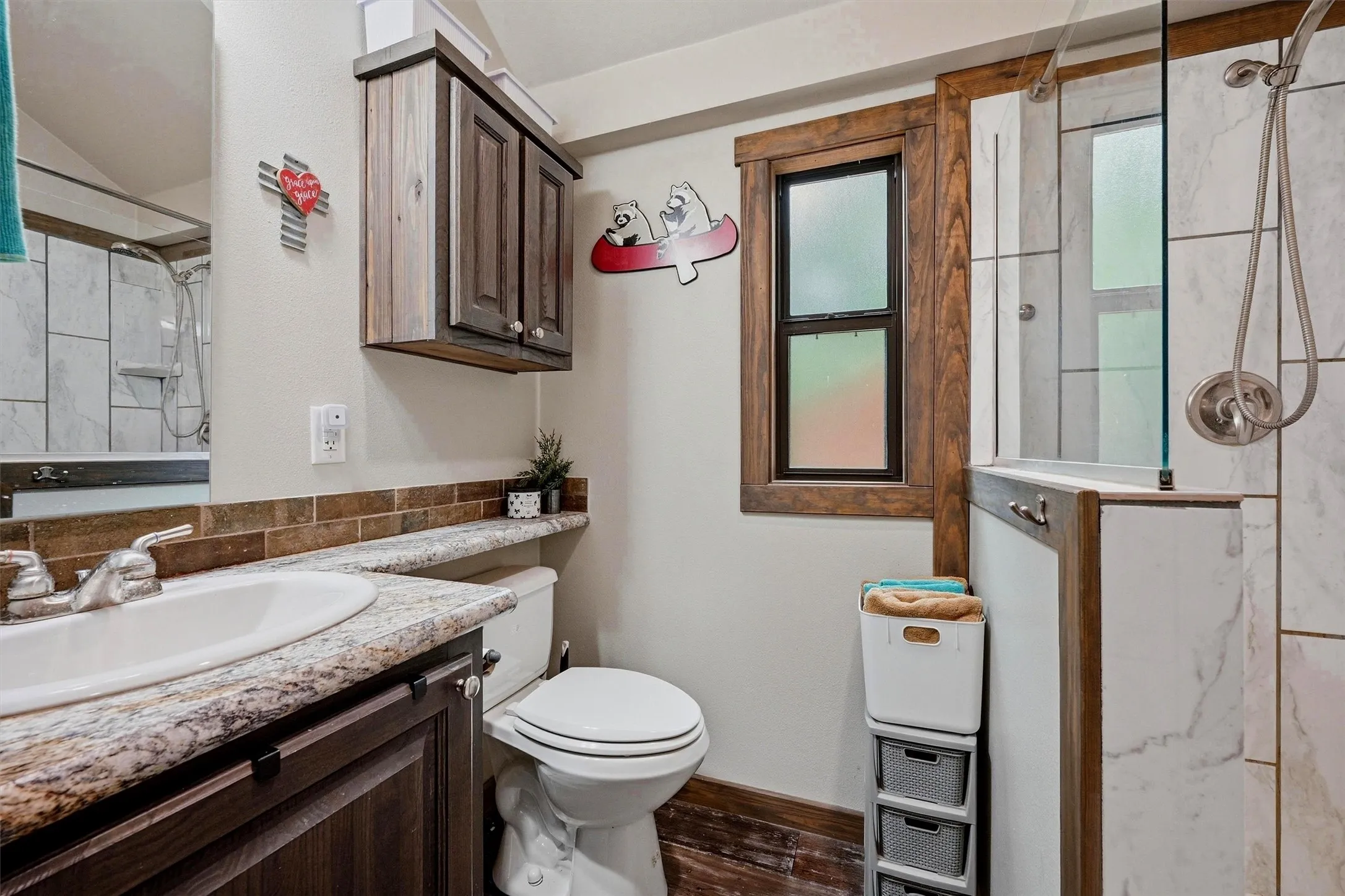 Bathroom featuring a dark wood-finish vanity with an integrated sink, granite-look countertop, and brick-patterned tile backsplash