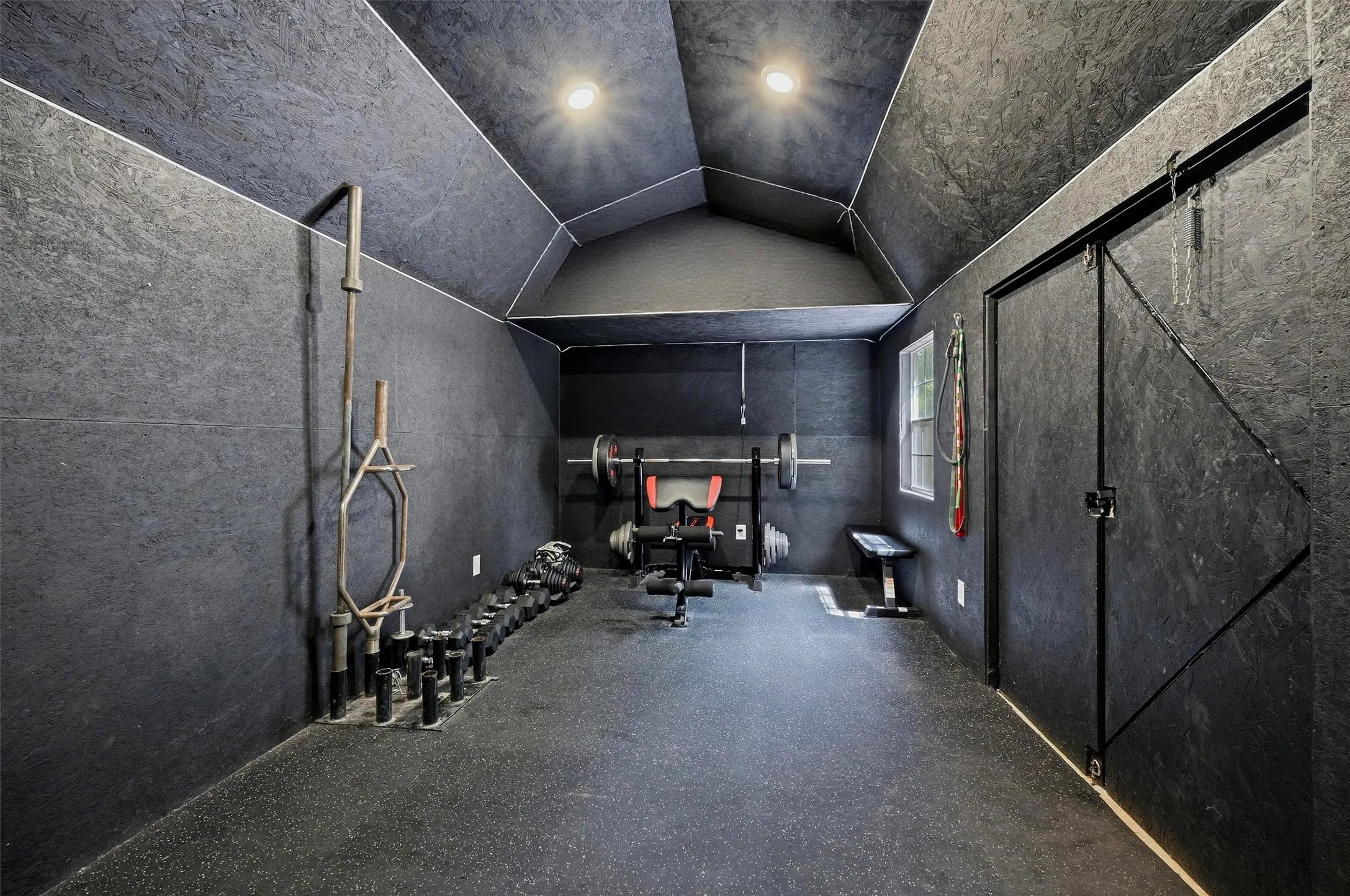 Dedicated space featuring dark-toned walls and ceilings, recessed lighting, and rubber flooring