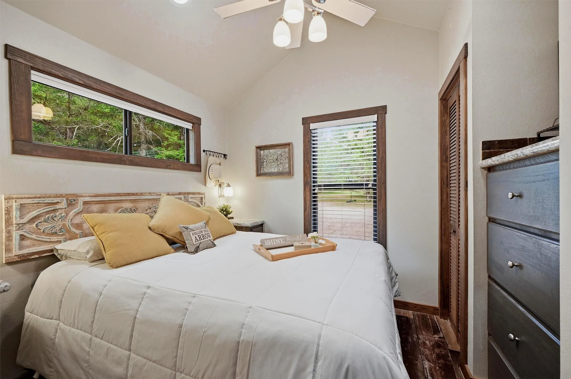 Bedroom featuring wood-finish flooring, wood-trimmed windows, and a ceiling fan with integrated lighting