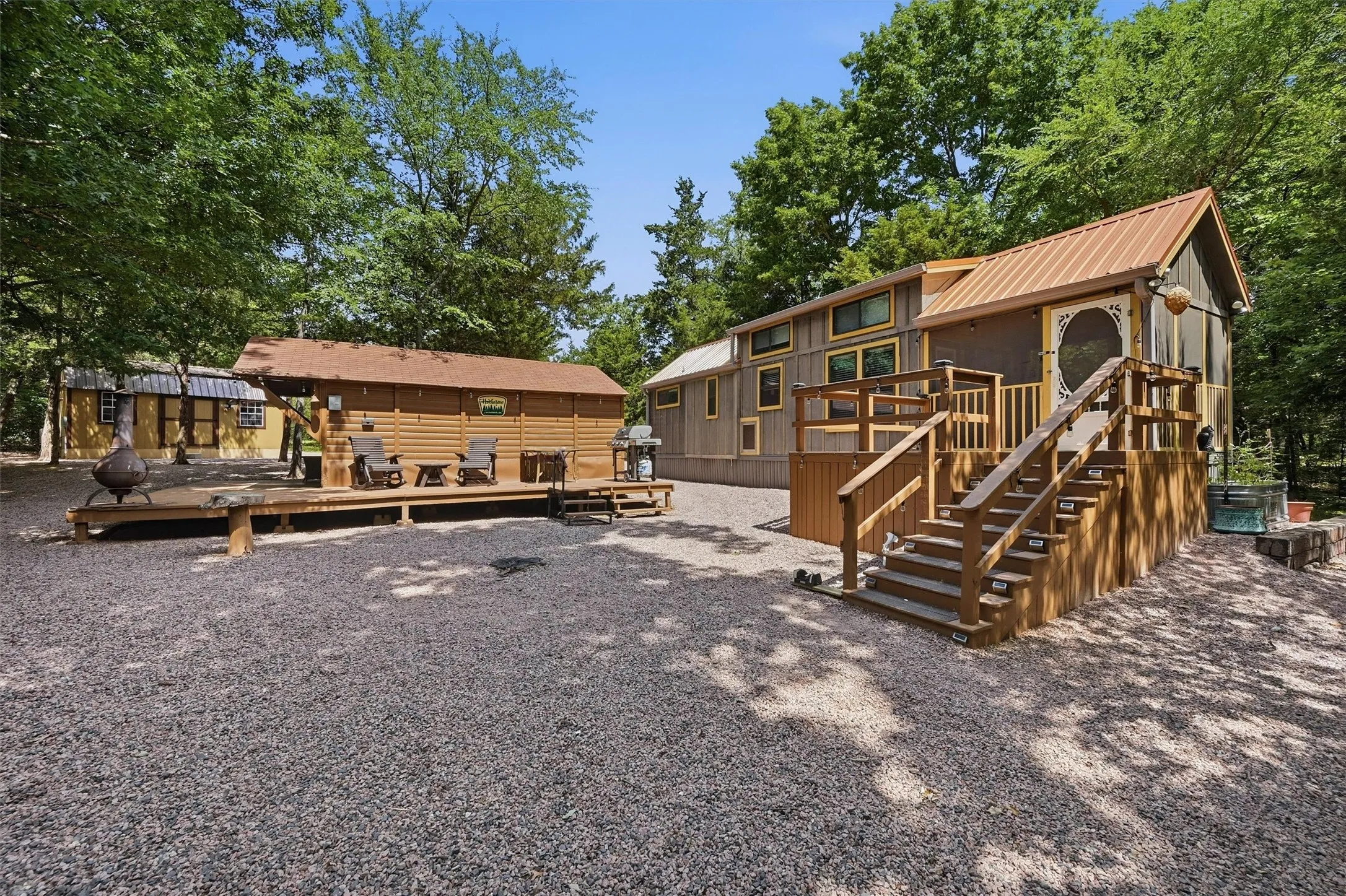 Multi-level property featuring a main structure with a metal roof and an elevated screened porch with wooden stairs