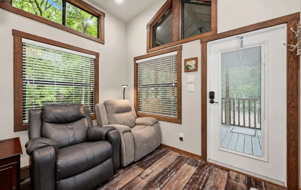 Wood-finish flooring with varying tones, multiple windows with blinds, a glass-paneled exterior door, and light-toned walls