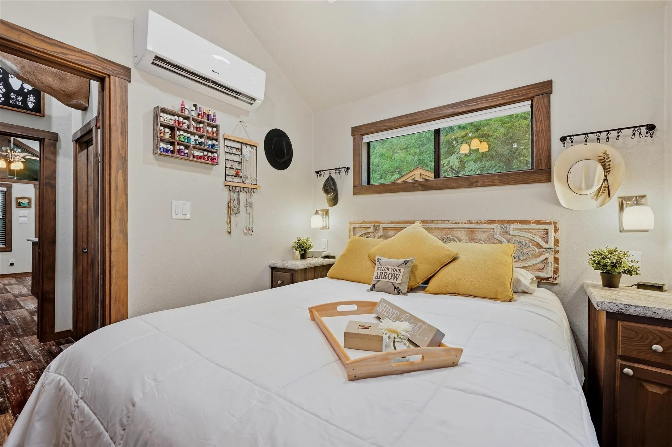 Bedroom with a built-in air conditioning unit, and a horizontal window with wood-finish trim