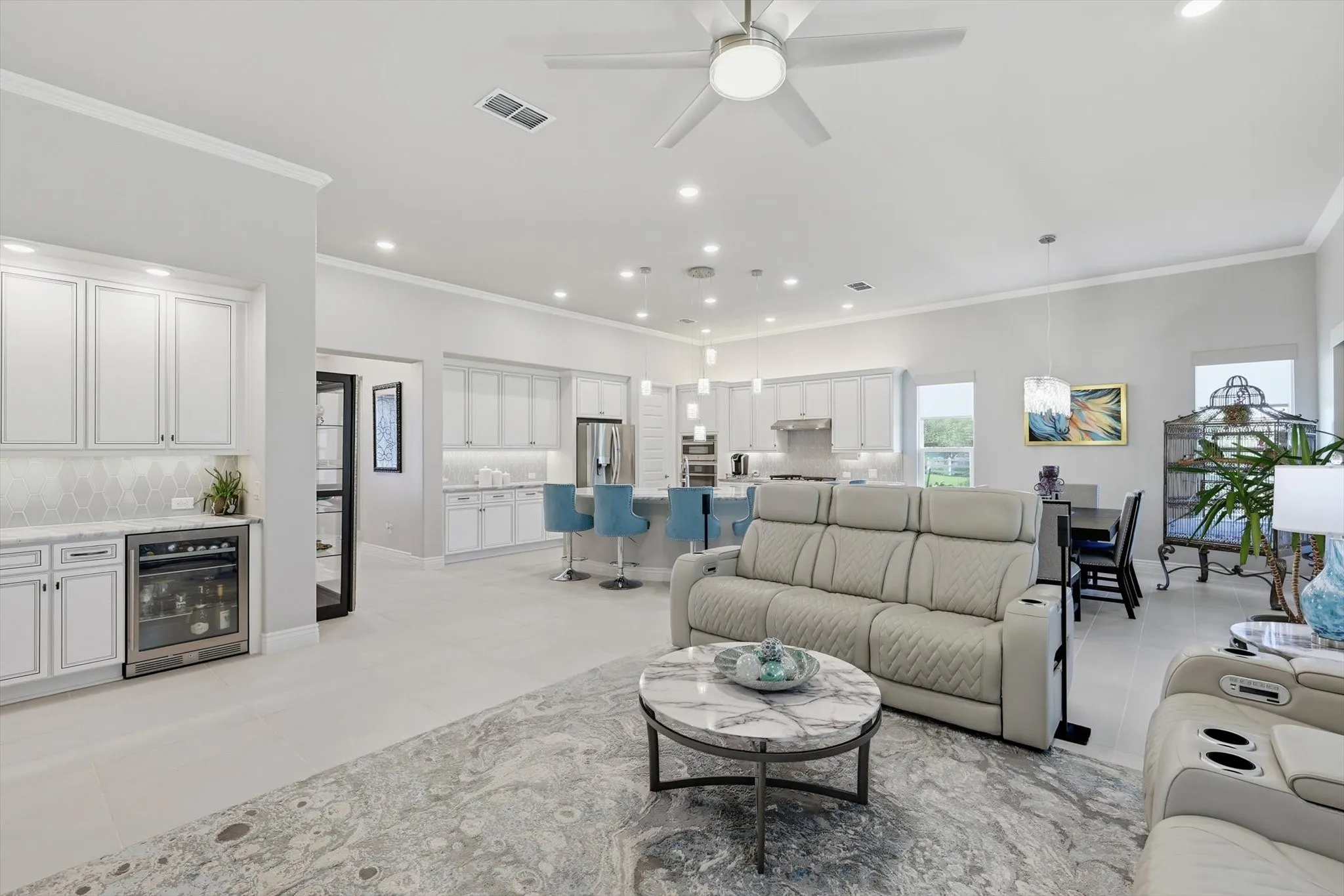 Open-concept living area with light tile flooring and crown molding