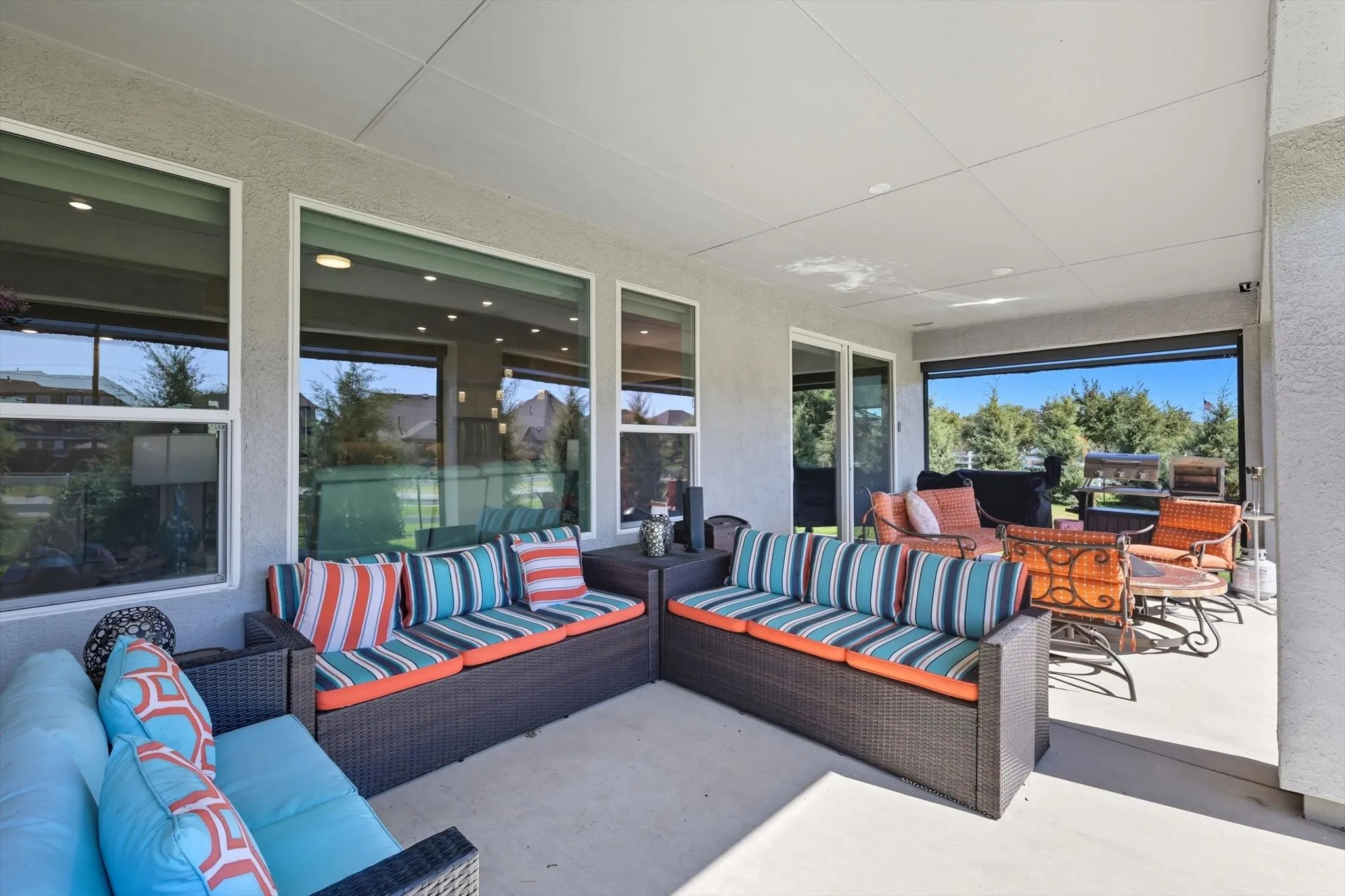 Covered patio area featuring a concrete surface, stucco exterior, multiple large windows, and a built-in outdoor screen