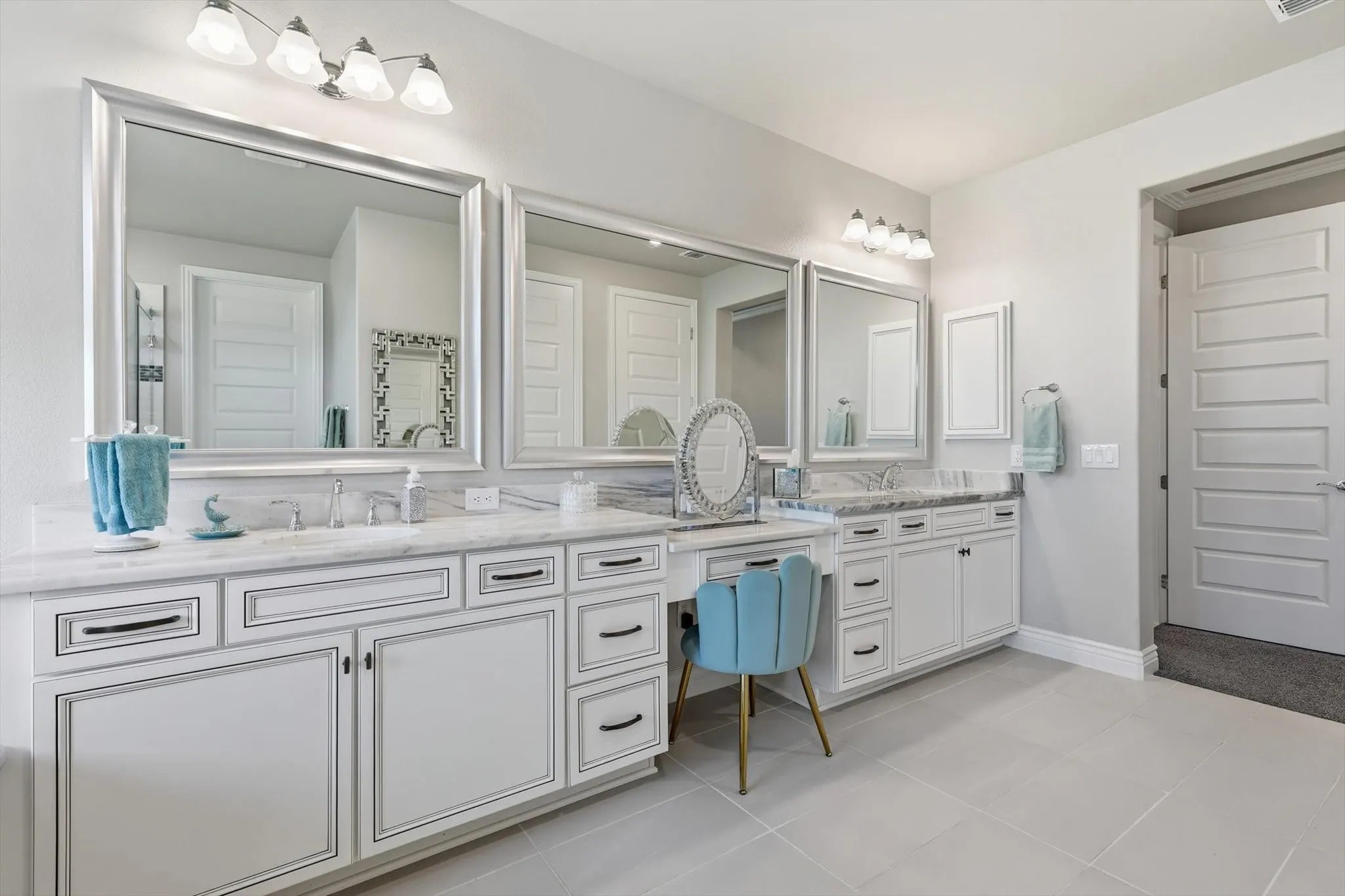 Spacious bathroom featuring dual vanities with white cabinetry, integrated sinks, and polished countertops