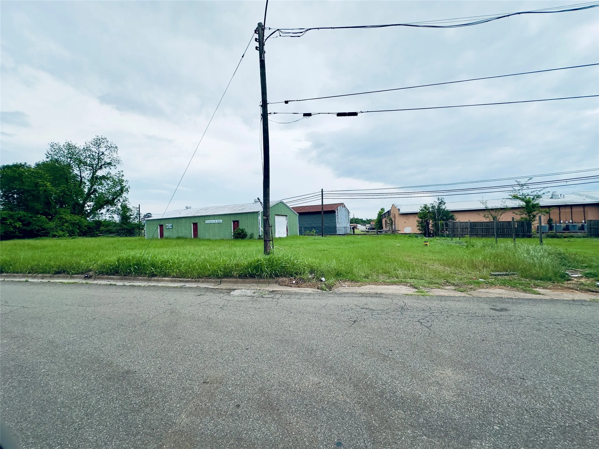 Expansive grassy lot featuring a green metal-sided building and a smaller adjacent structure
