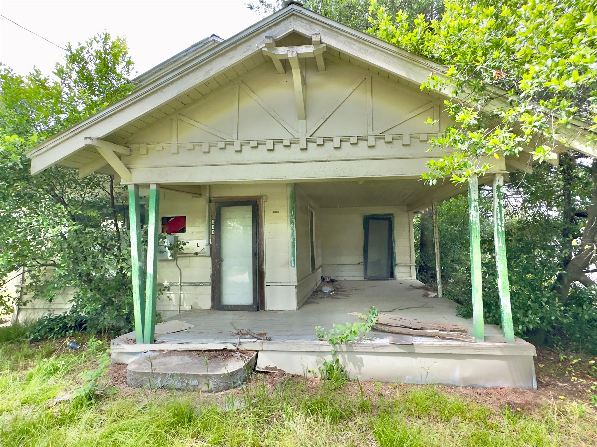 Front exterior featuring a covered porch, gabled roofline, visible structural elements, and a concrete foundation