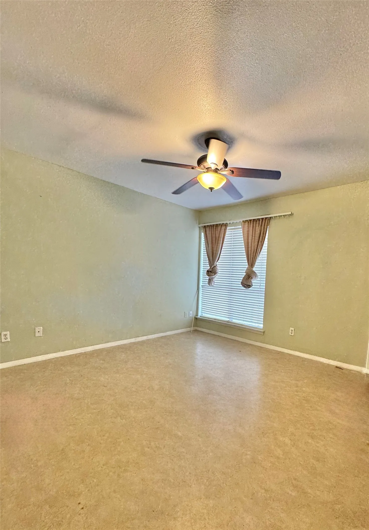 Spacious room featuring light-toned walls, a ceiling fan with integrated lighting, window blinds, and light-toned flooring