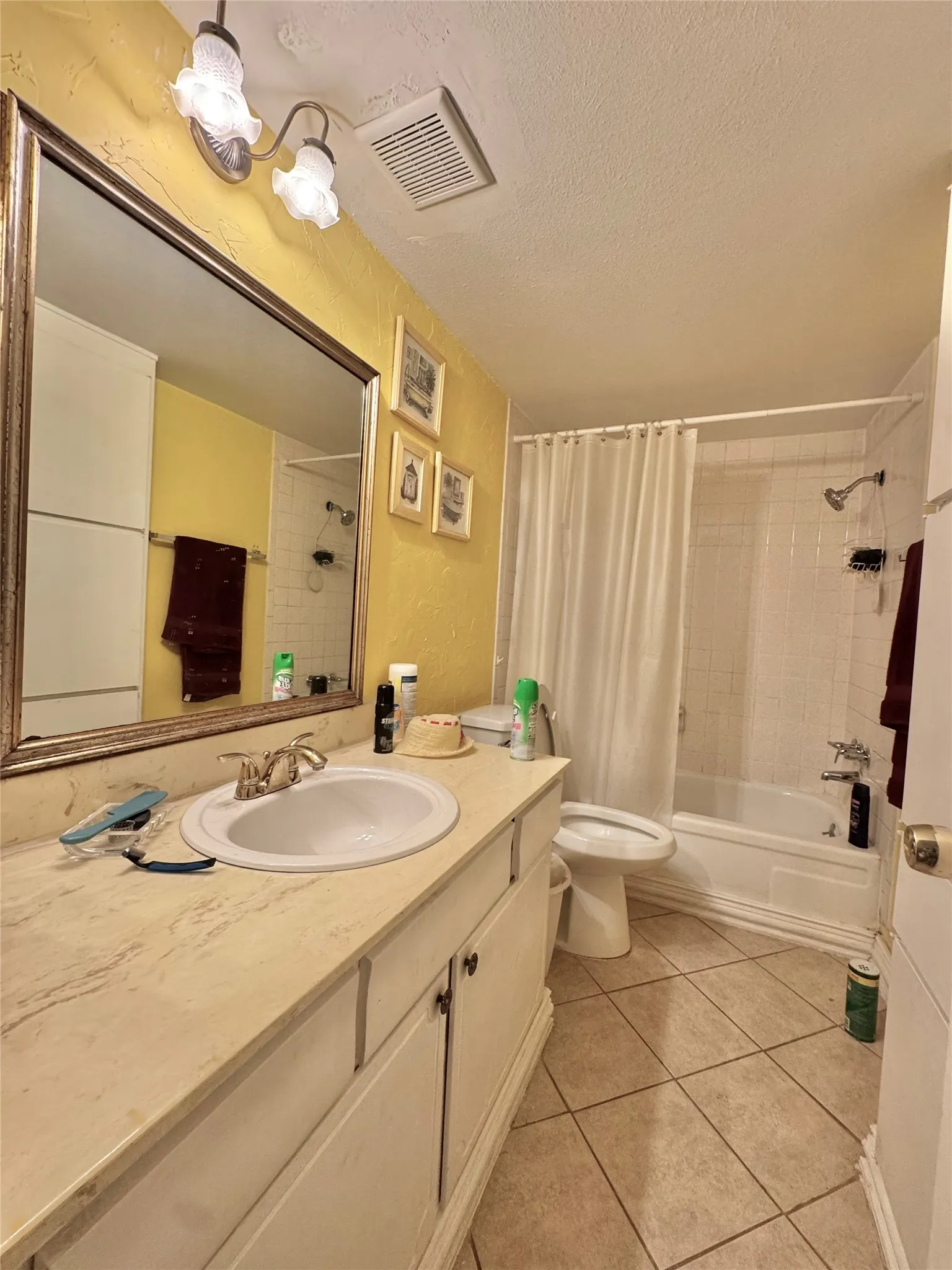 Bathroom featuring a vanity with an integrated sink, a rectangular mirror, a shower-over-tub combination with white subway tile surround, and neutral square floor tiling