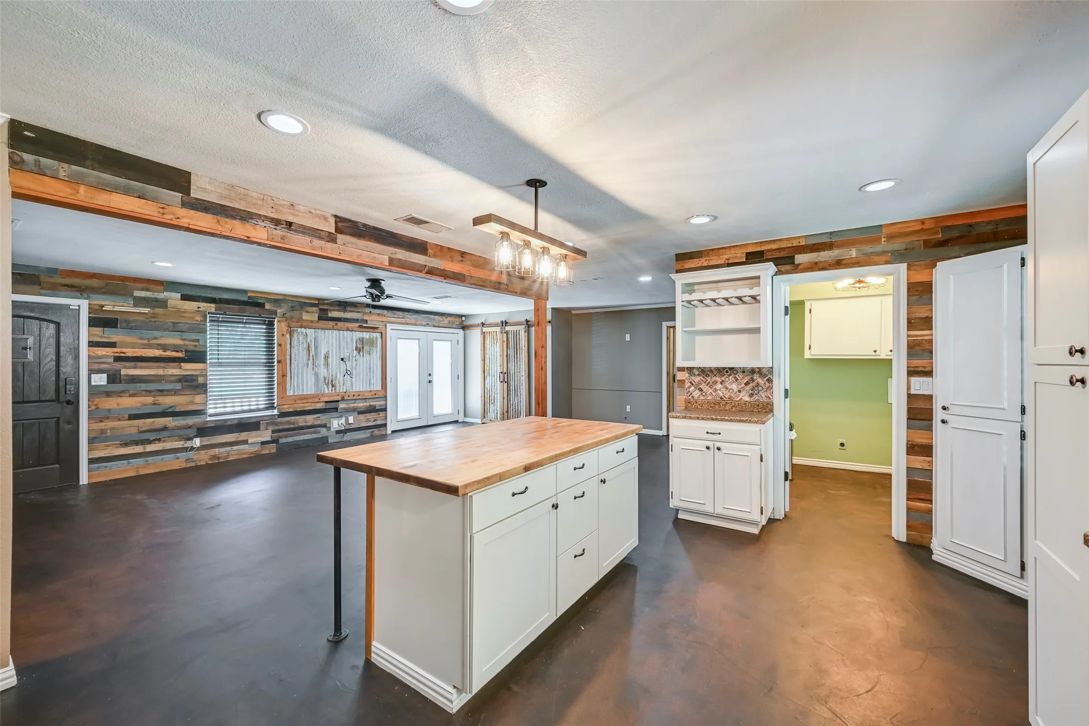 Spacious interior featuring dark concrete flooring and a light wood-finish island with integrated storage