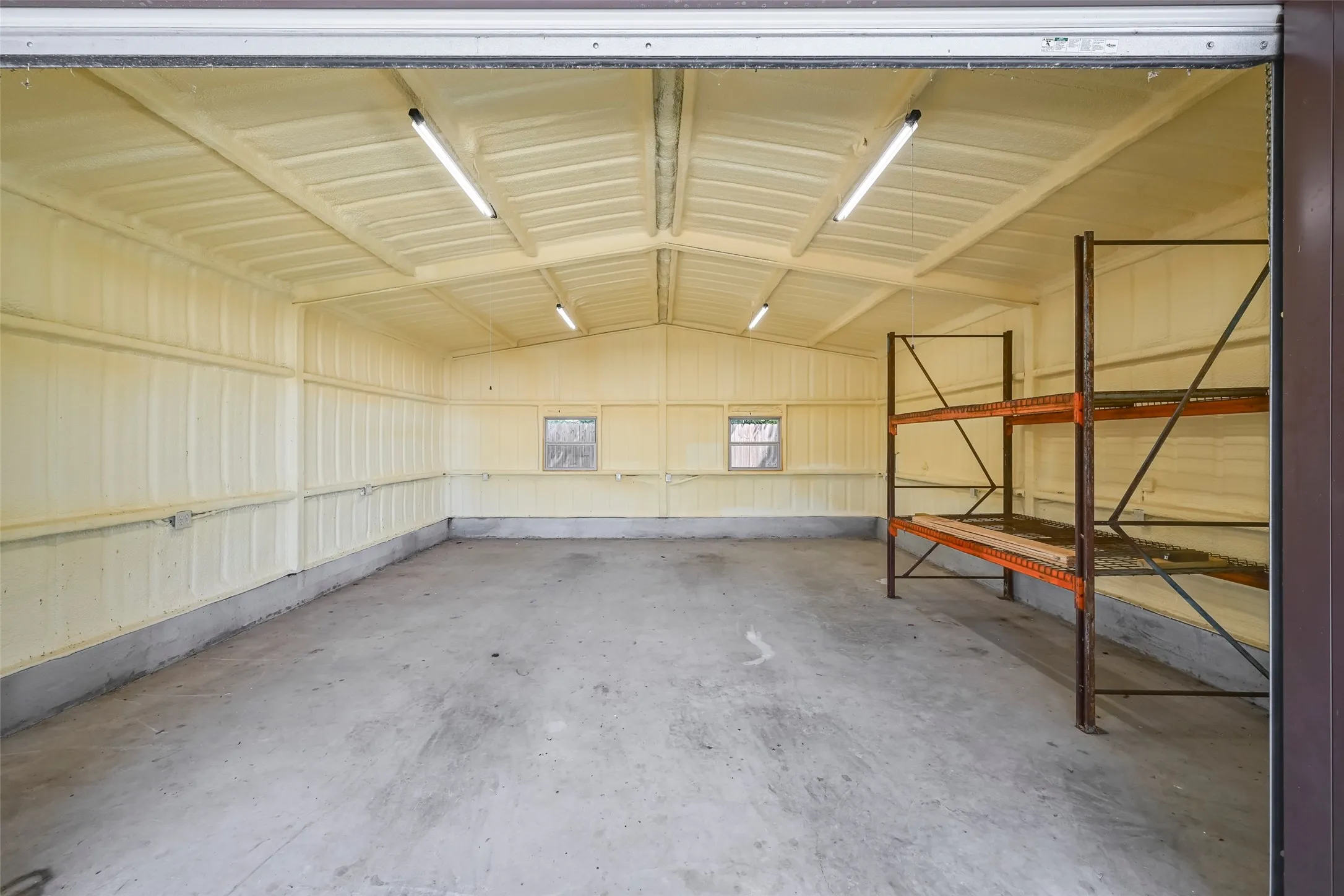 Spacious interior featuring concrete flooring, insulated walls and ceiling, and multiple overhead fluorescent light fixtures