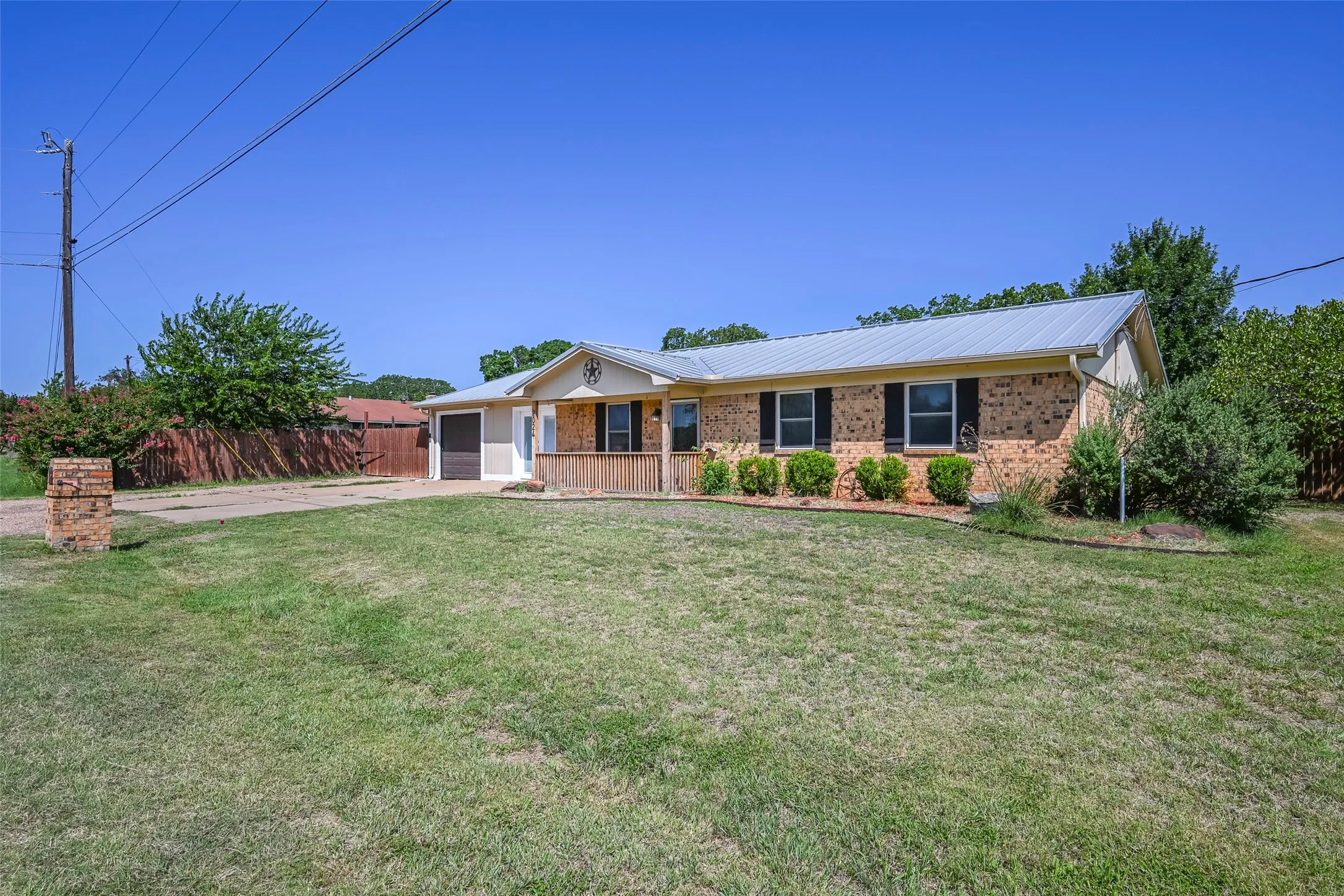Single-story residence featuring a metal roof, brick exterior, and a covered front porch with wood columns