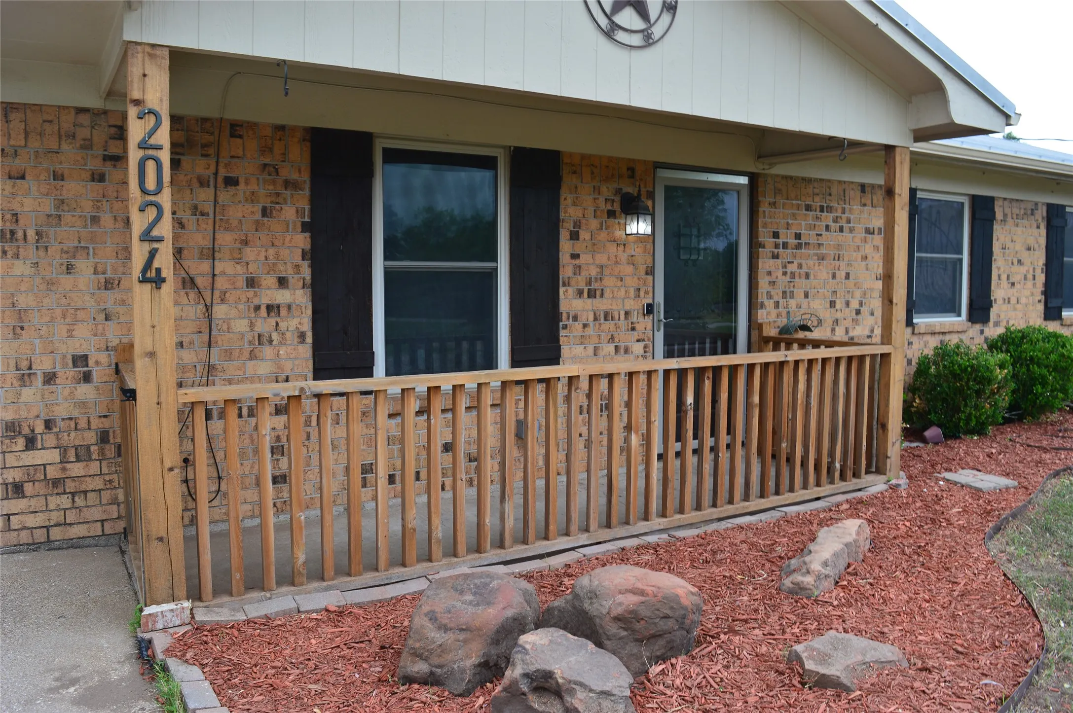 Brick facade with a covered porch featuring wood posts and railing