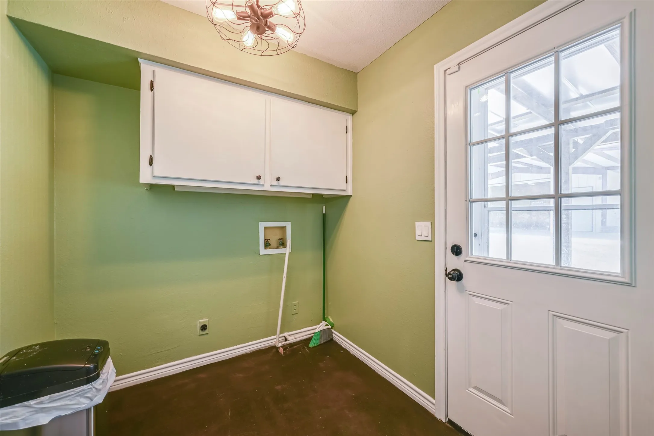 Dedicated utility area featuring a windowed exterior door, built-in upper cabinetry, appliance hookups, and a decorative ceiling light fixture