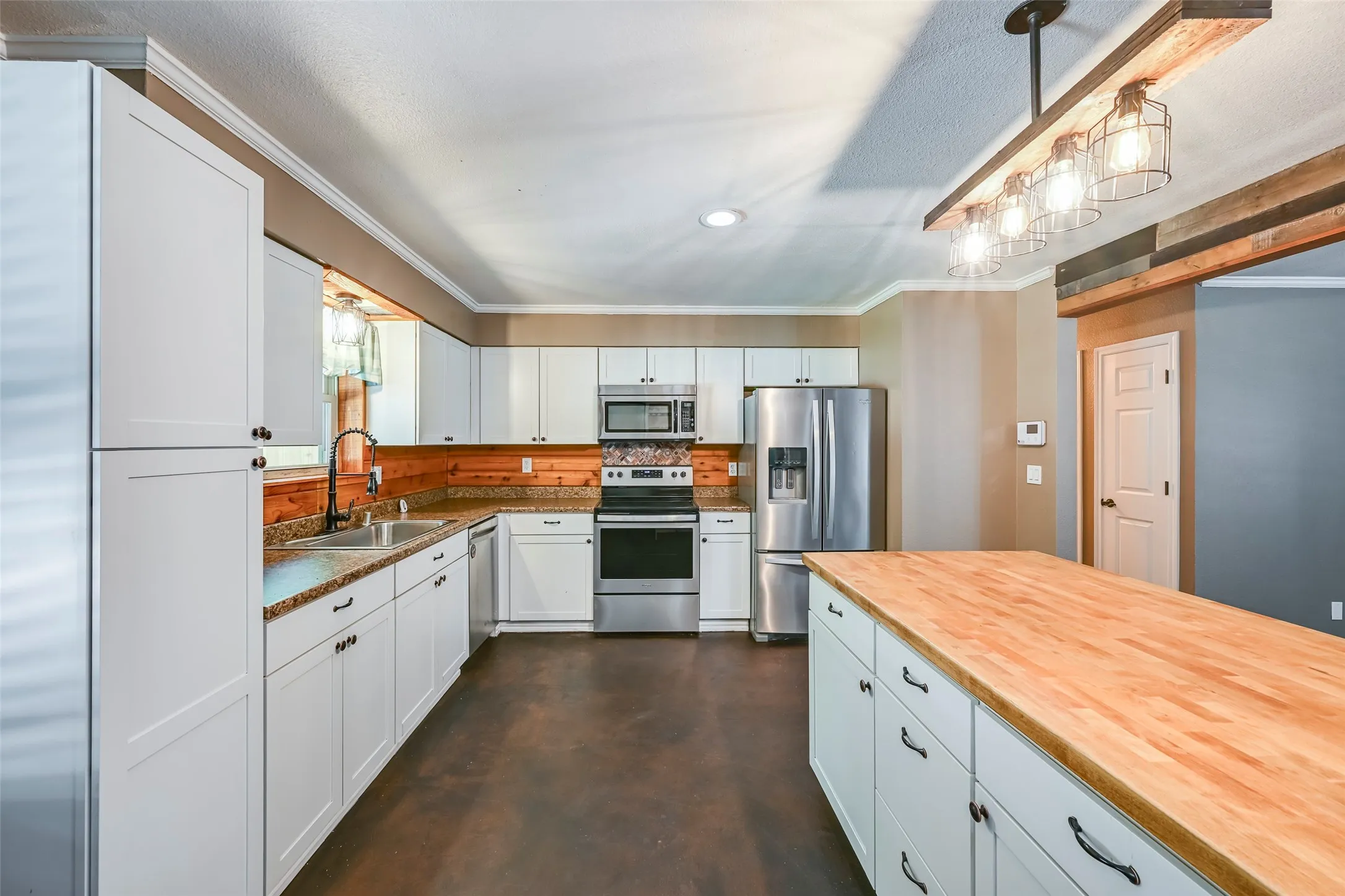 Kitchen featuring white cabinetry, granite-look countertops, a wooden backsplash, stainless steel appliances, and a central island with a wood-finish countertop