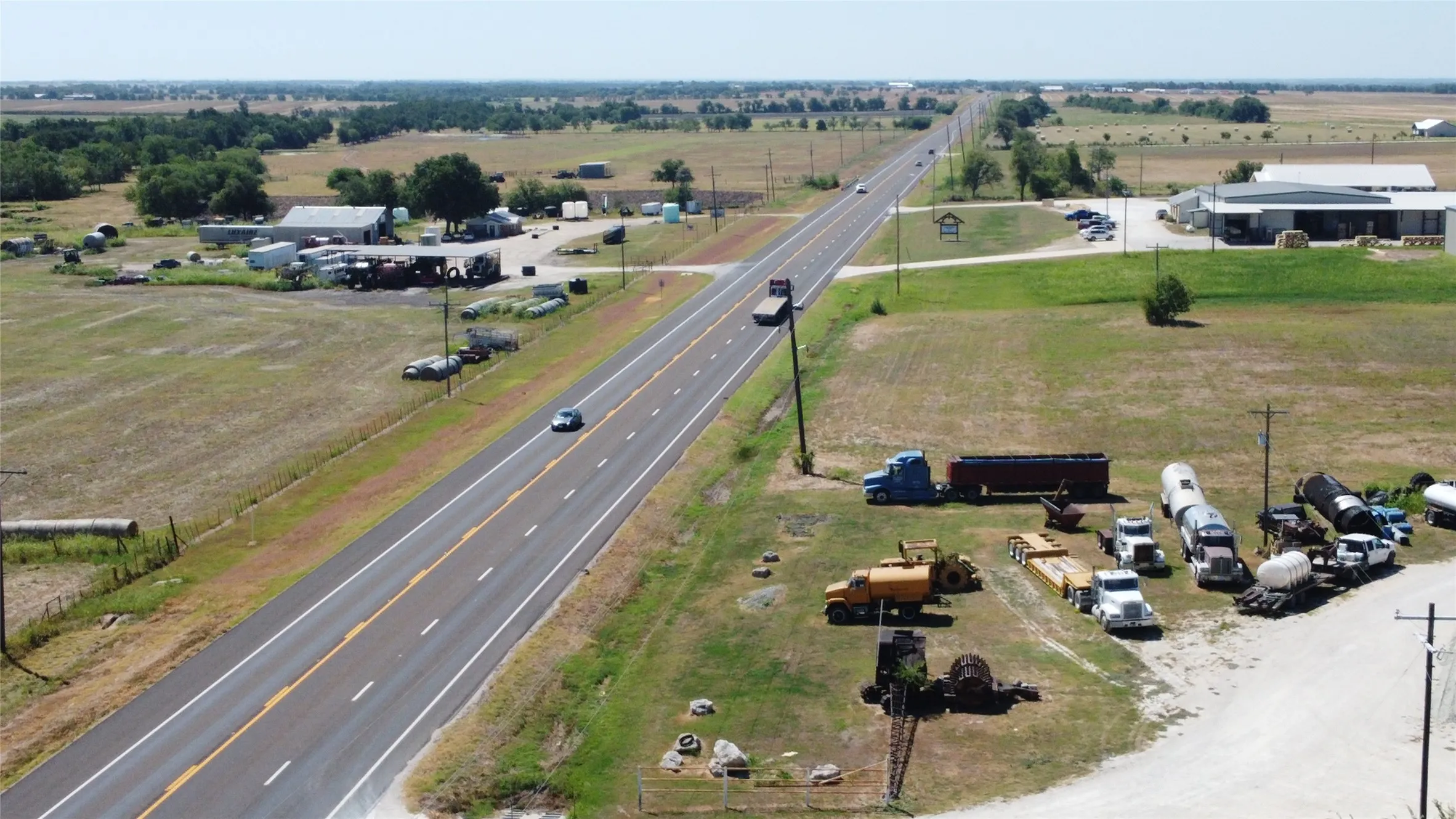 Expansive rural landscape featuring a paved highway and visible structures