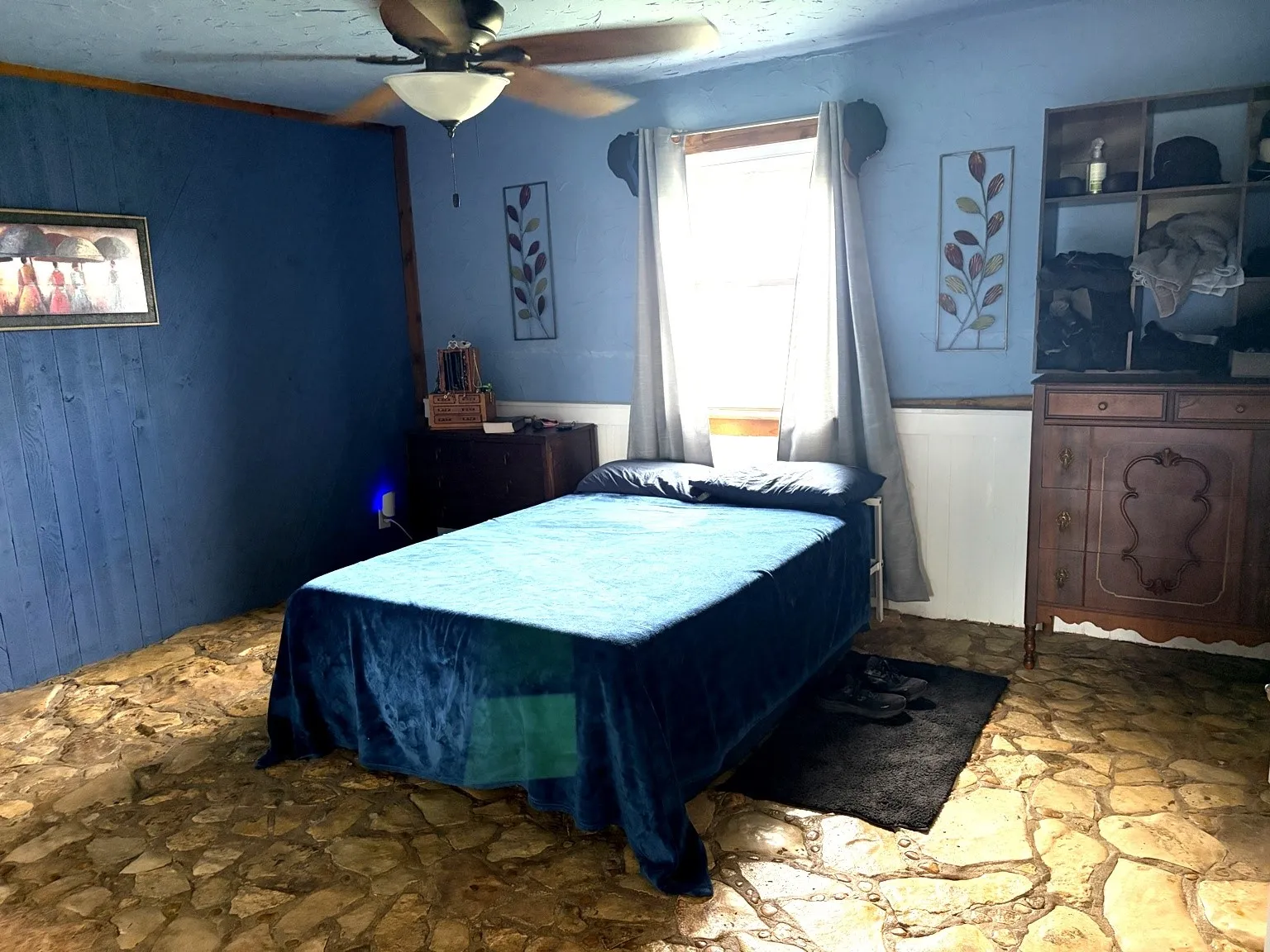 Stone flooring throughout the room with a paneled accent wall