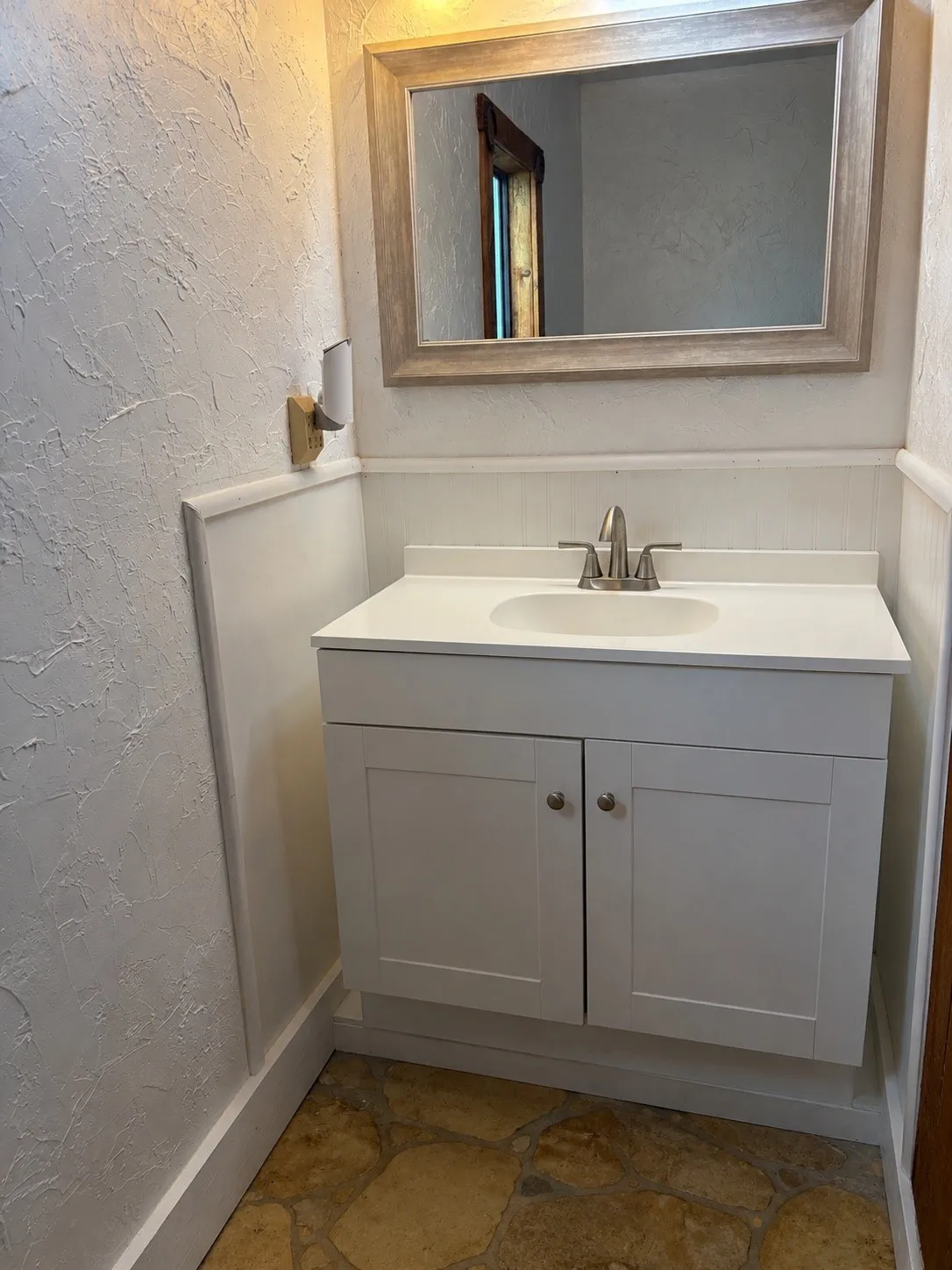 Bathroom vanity featuring a white countertop with integrated sink, brushed nickel faucet, and shaker-style cabinetry