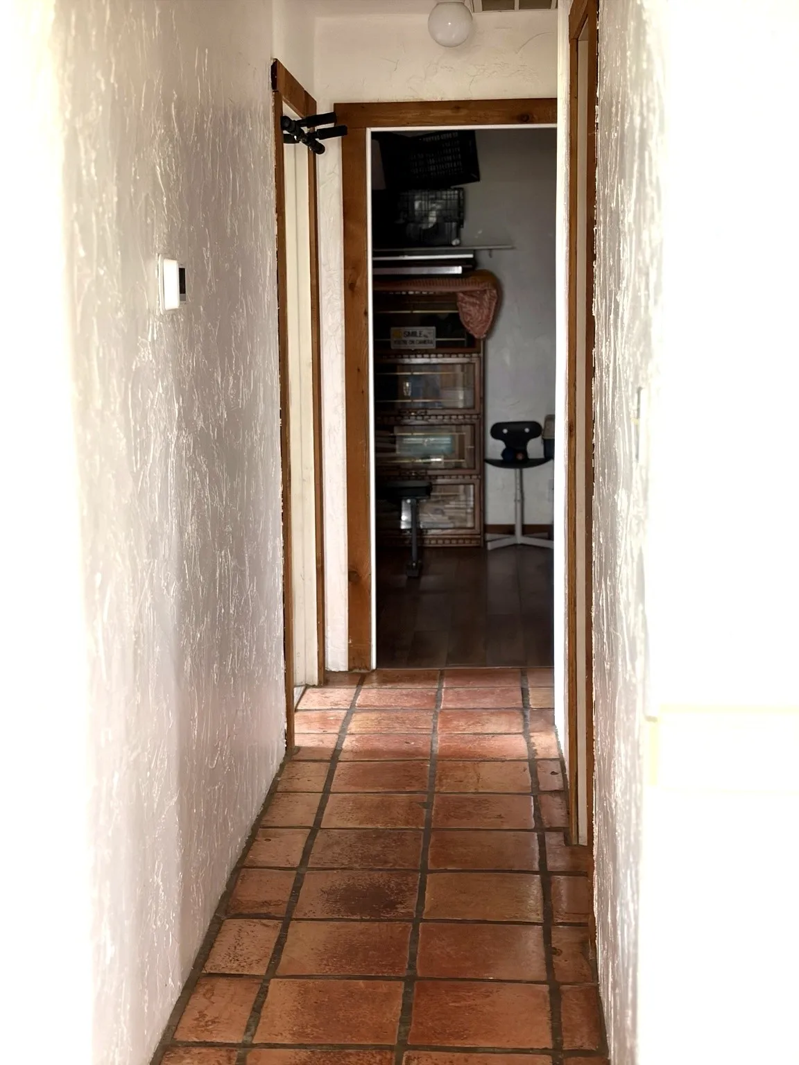 Terracotta tile flooring extending through the hallway, complemented by textured white walls