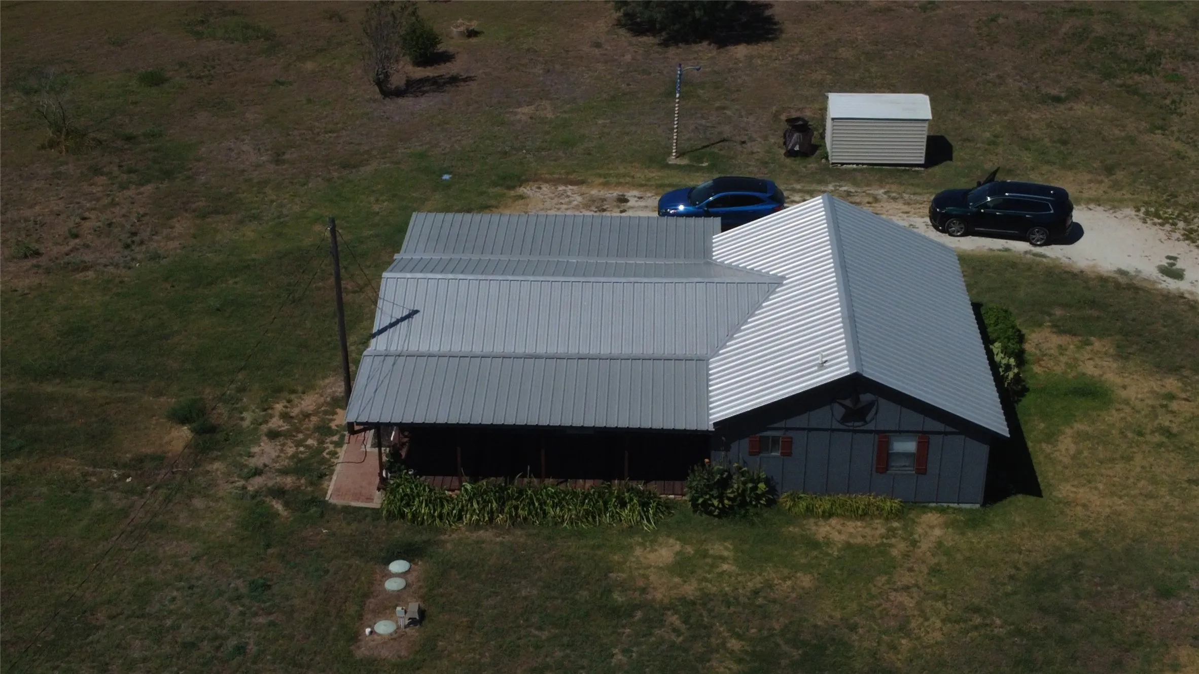 Single-story residence featuring a metal roof, dark exterior siding, and a covered porch