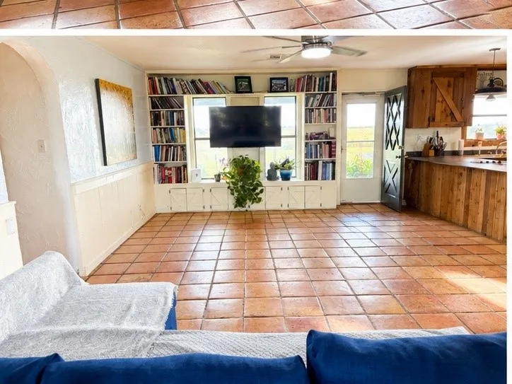 Living area featuring terracotta tile flooring, built-in shelving, a ceiling fan, a barn door, and a kitchen island with a wooden countertop