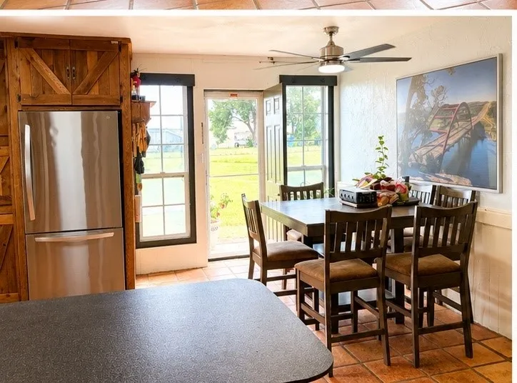 Kitchen with terracotta-style tile flooring, stainless steel refrigerator, and wood-paneled cabinetry
