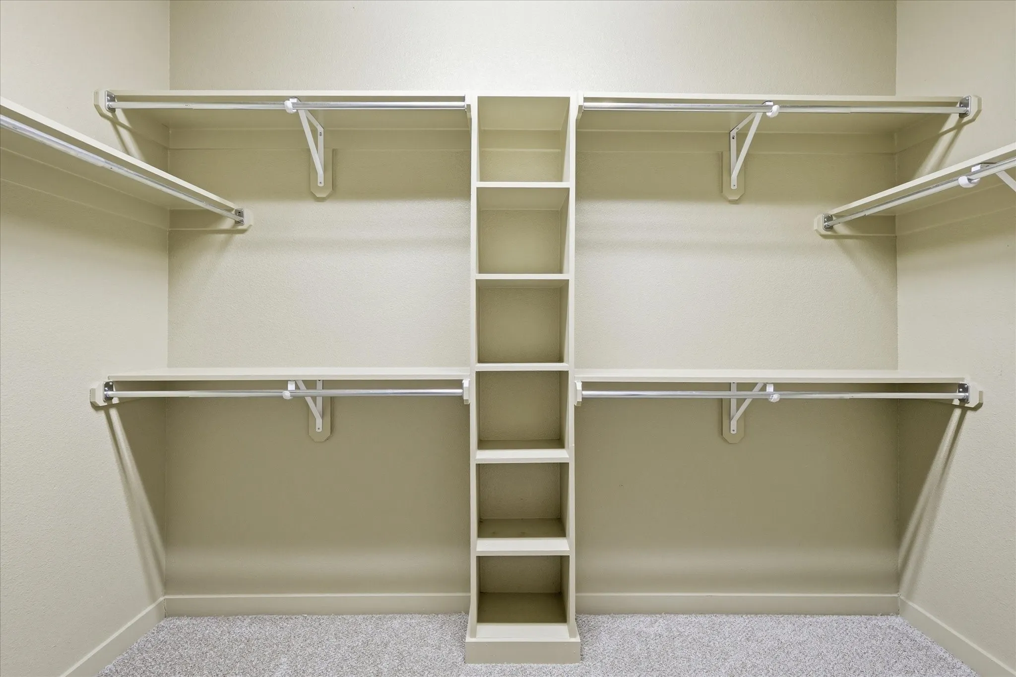 Walk-in closet featuring built-in shelving, multiple hanging rods, corner shelving, wall-to-wall carpeting, and neutral wall paint