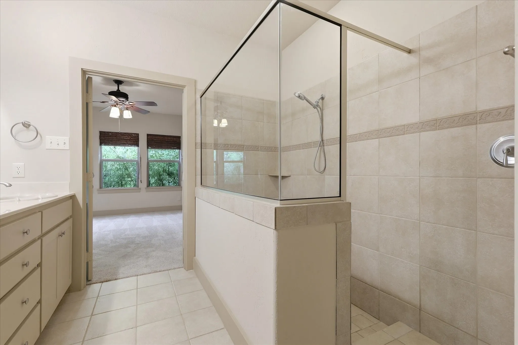Spacious bathroom featuring a glass-enclosed shower with tiled walls and a built-in shelf