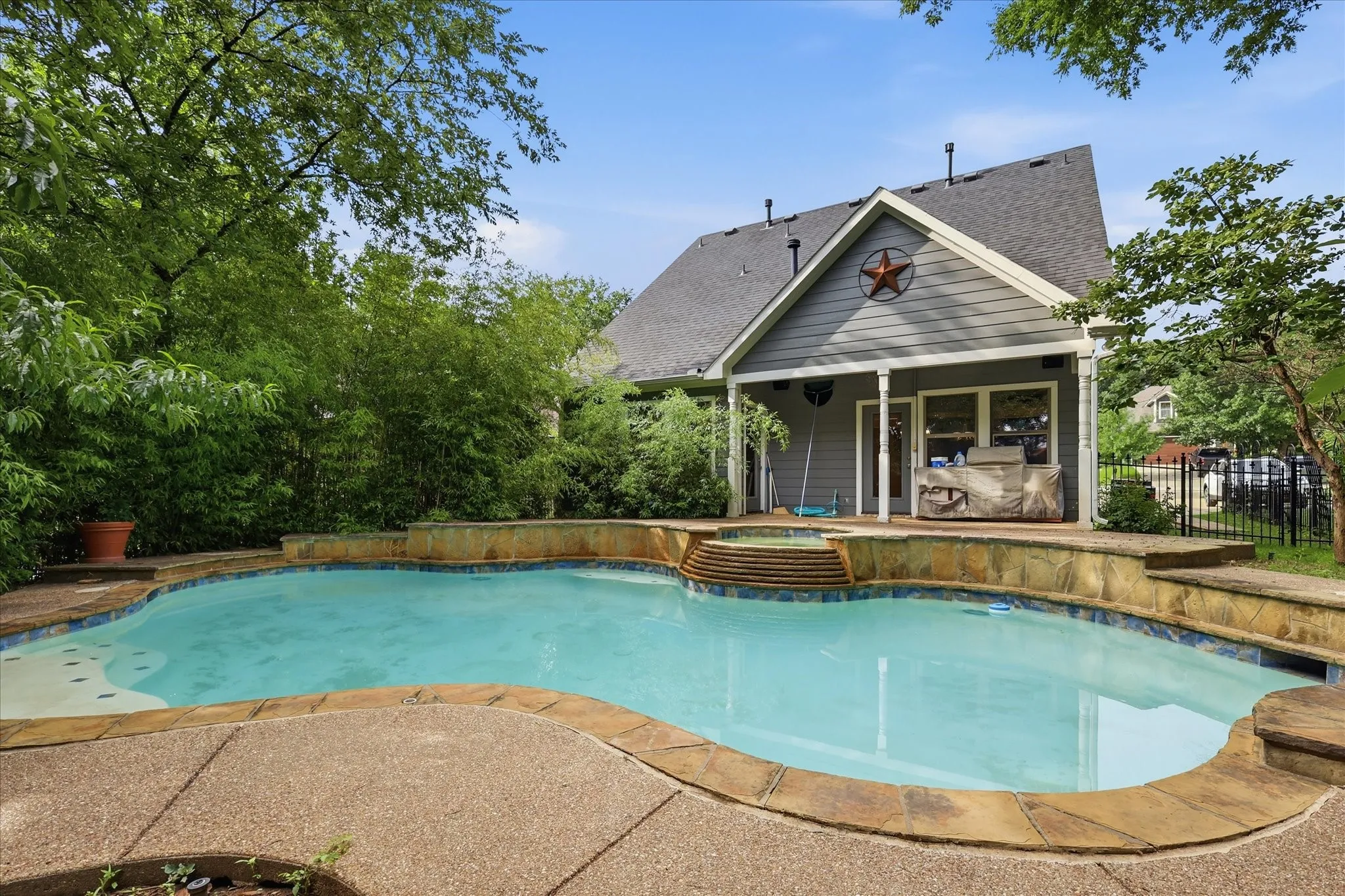 Custom-shaped swimming pool featuring a stone surround and integrated spa with tiered steps