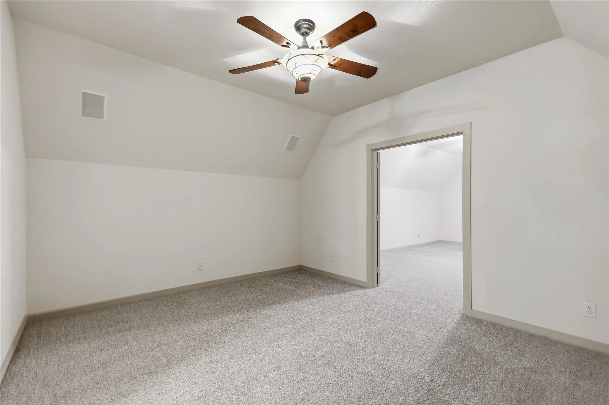 Carpeted room featuring a sloped ceiling and an overhead ceiling fan with integrated lighting