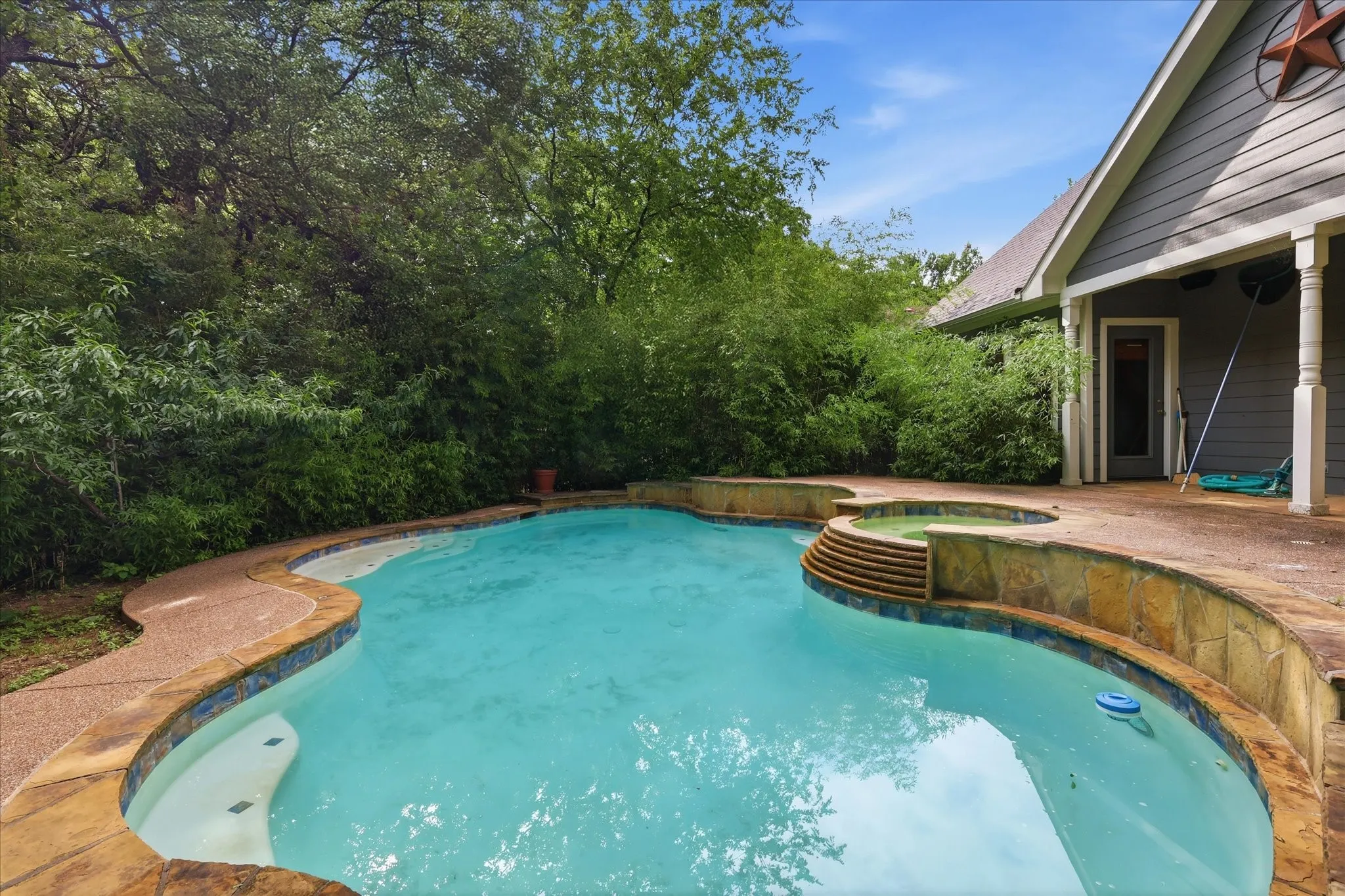 Curved swimming pool with integrated spa and stone surround