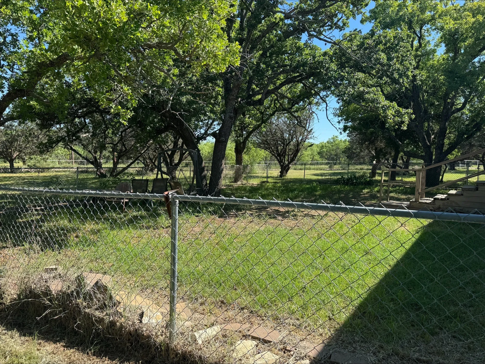 Fenced front yard with beautiful trees.