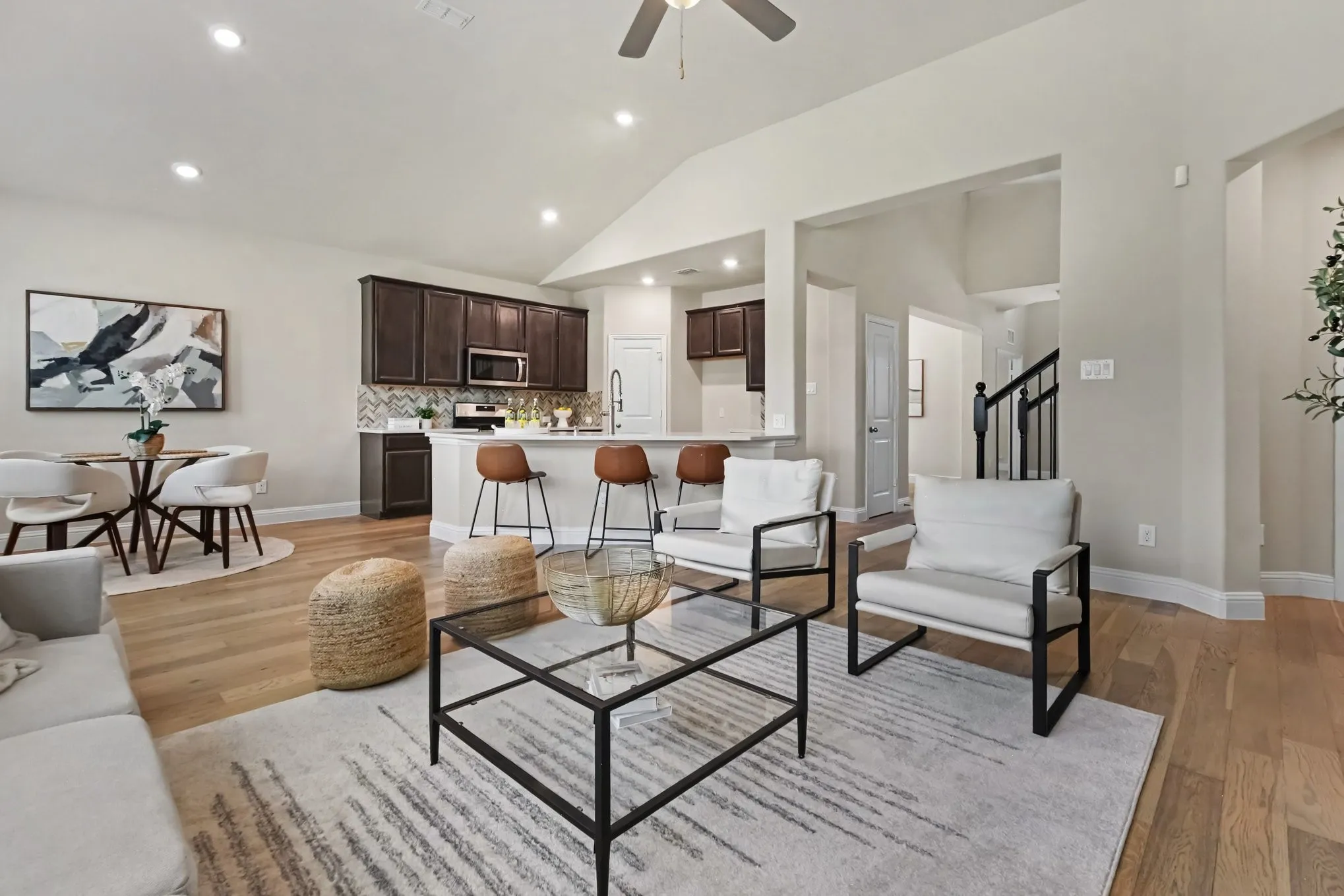 Vaulted ceilings, wood-finish flooring, kitchen with dark wood cabinetry, breakfast bar, and stainless steel appliances