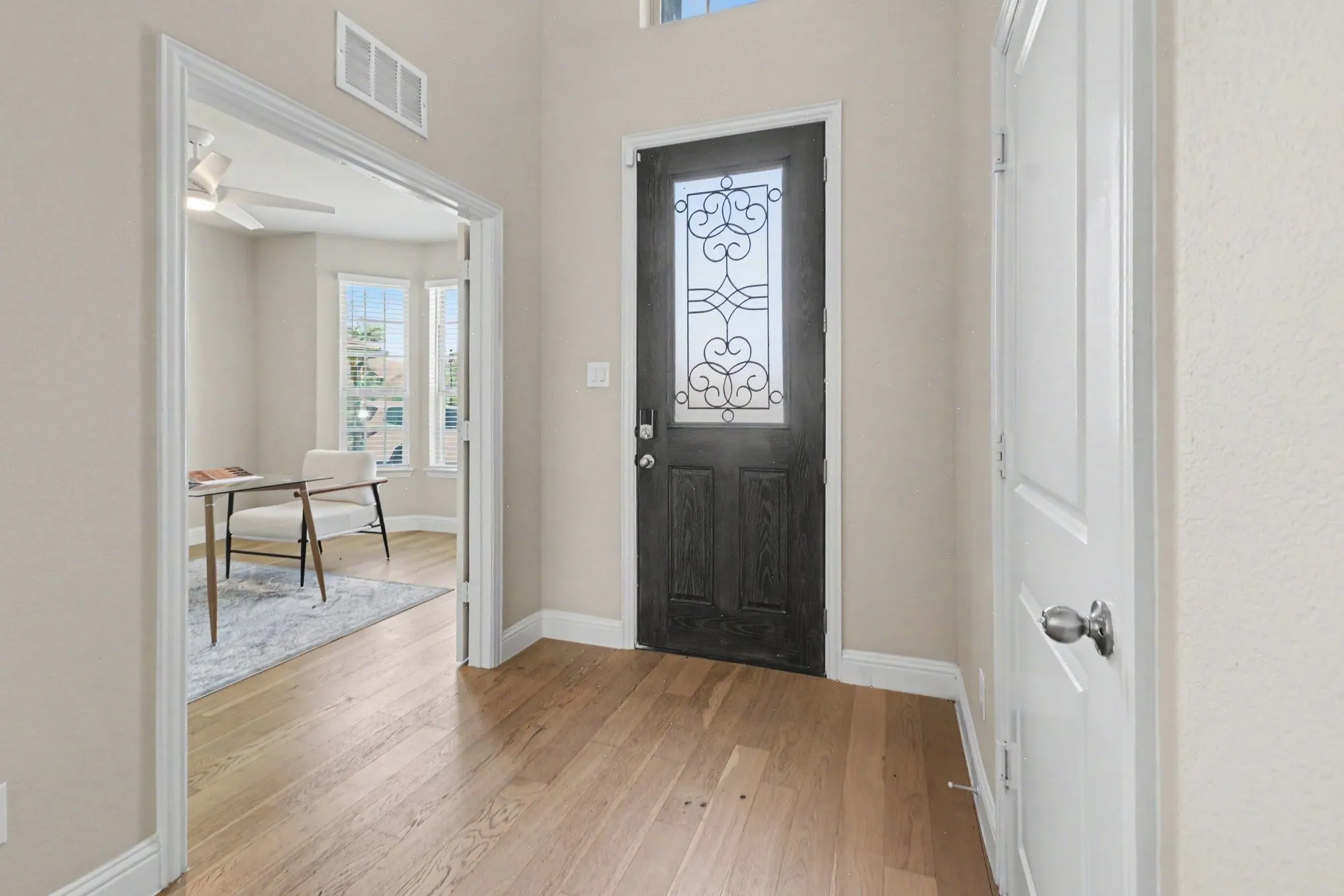 Wood-finish flooring throughout, decorative glass entry door, bay window configuration, and a ceiling fan with integrated lighting