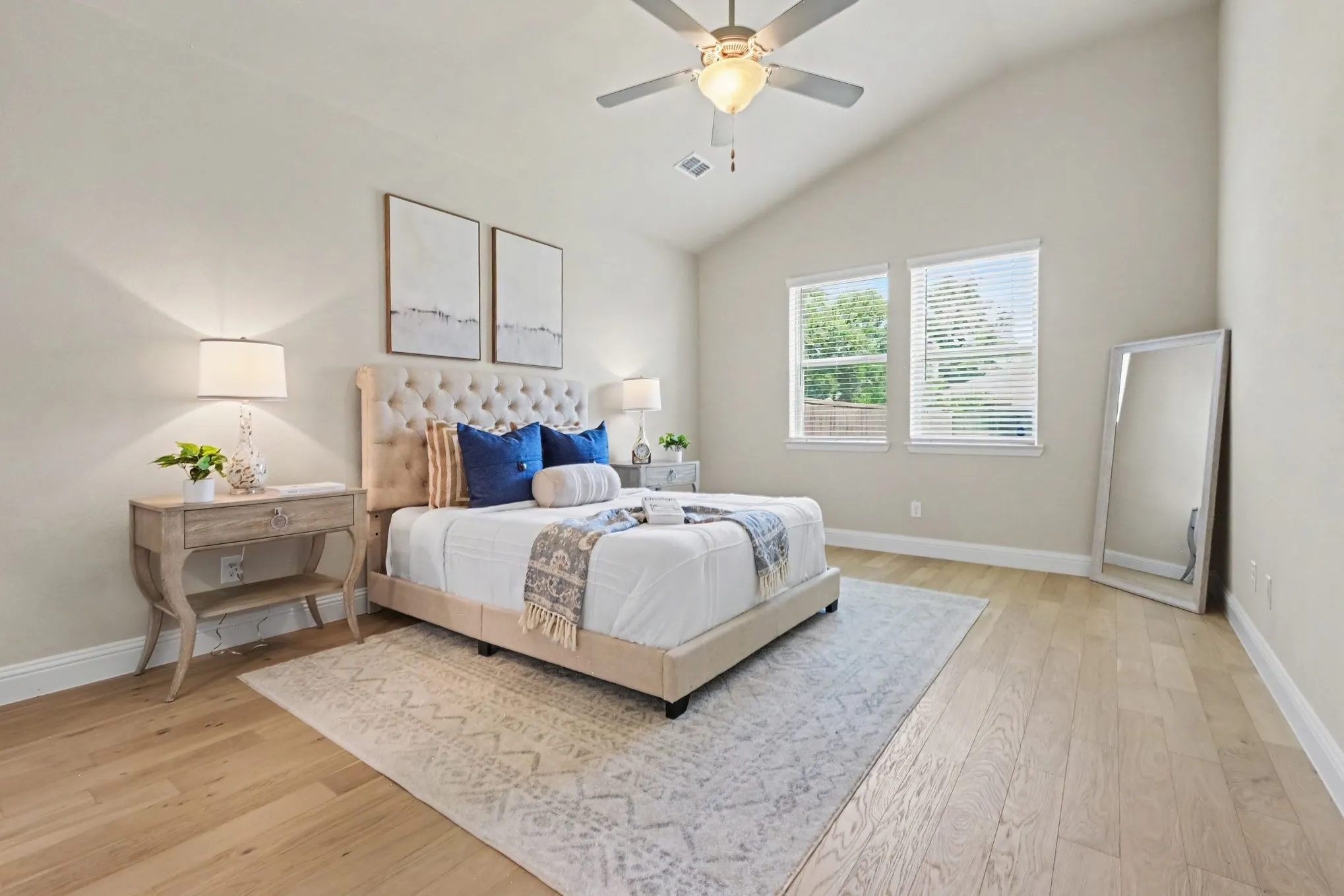Vaulted ceiling, wood-finish flooring, ceiling fan with integrated lighting, and two windows with blinds
