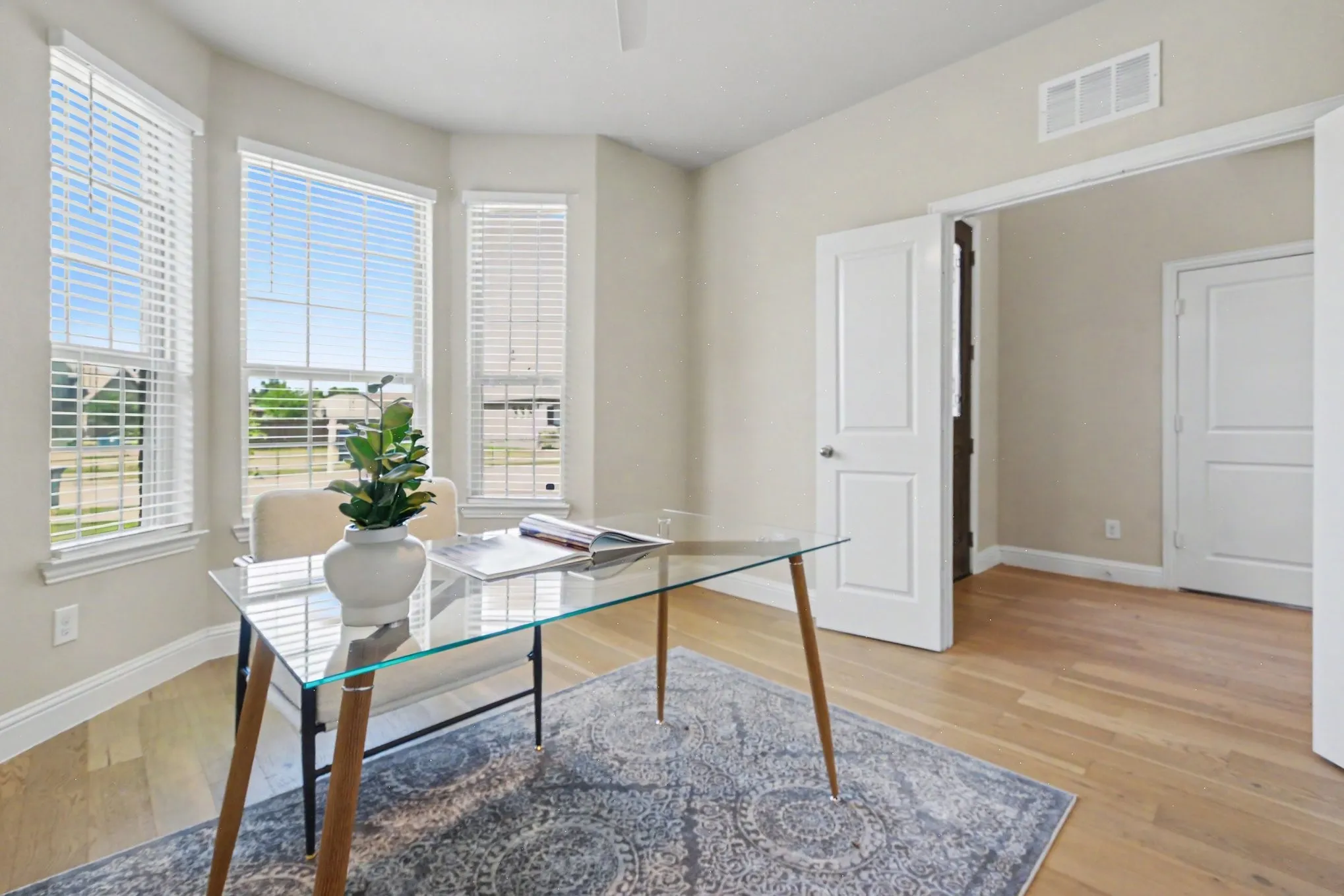 Wood-finish flooring, multiple windows with blinds, white paneled doors, and light-toned wall paint