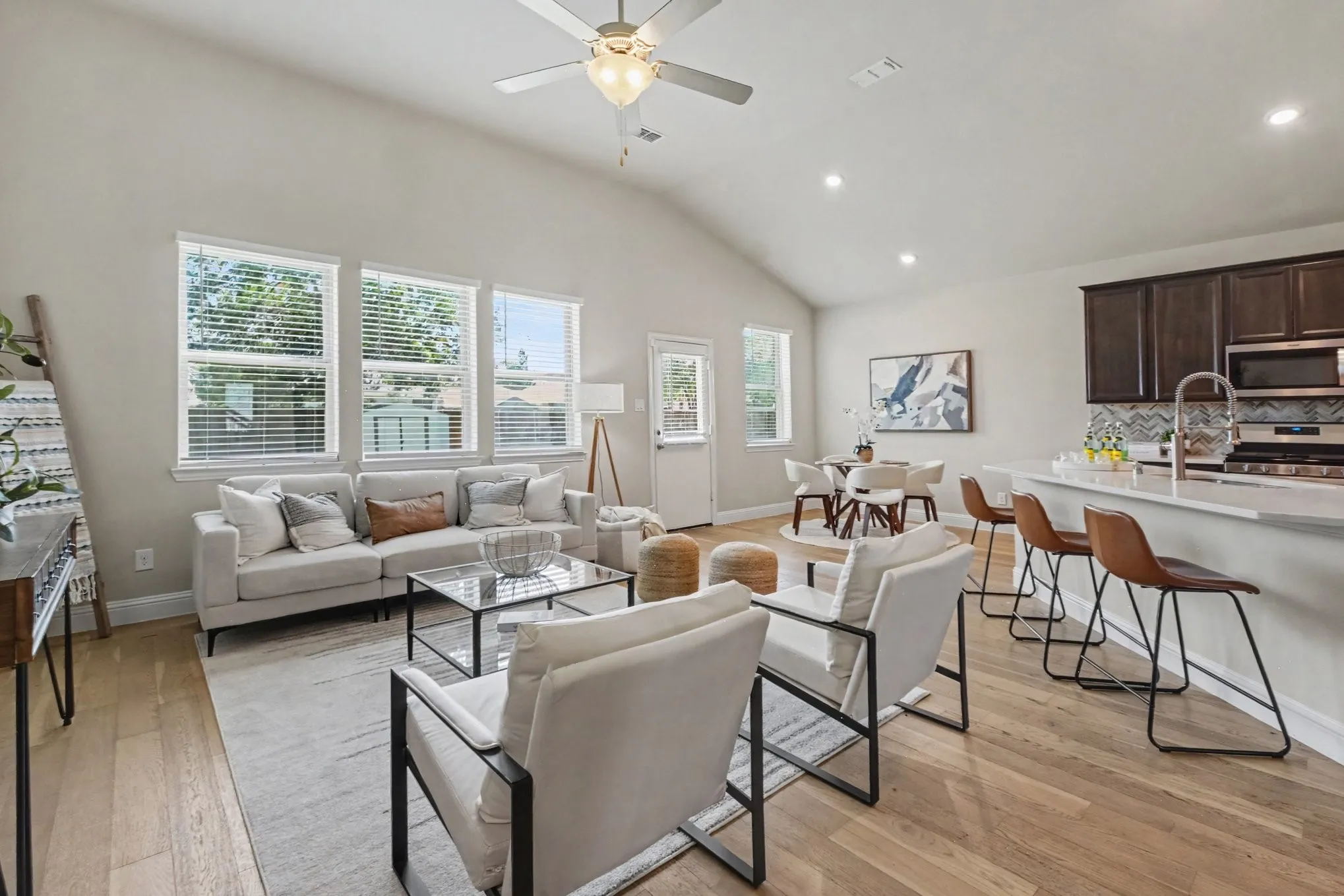 Vaulted ceiling with ceiling fan, wood-finish flooring, recessed lighting, kitchen island with countertop, and dark wood cabinetry