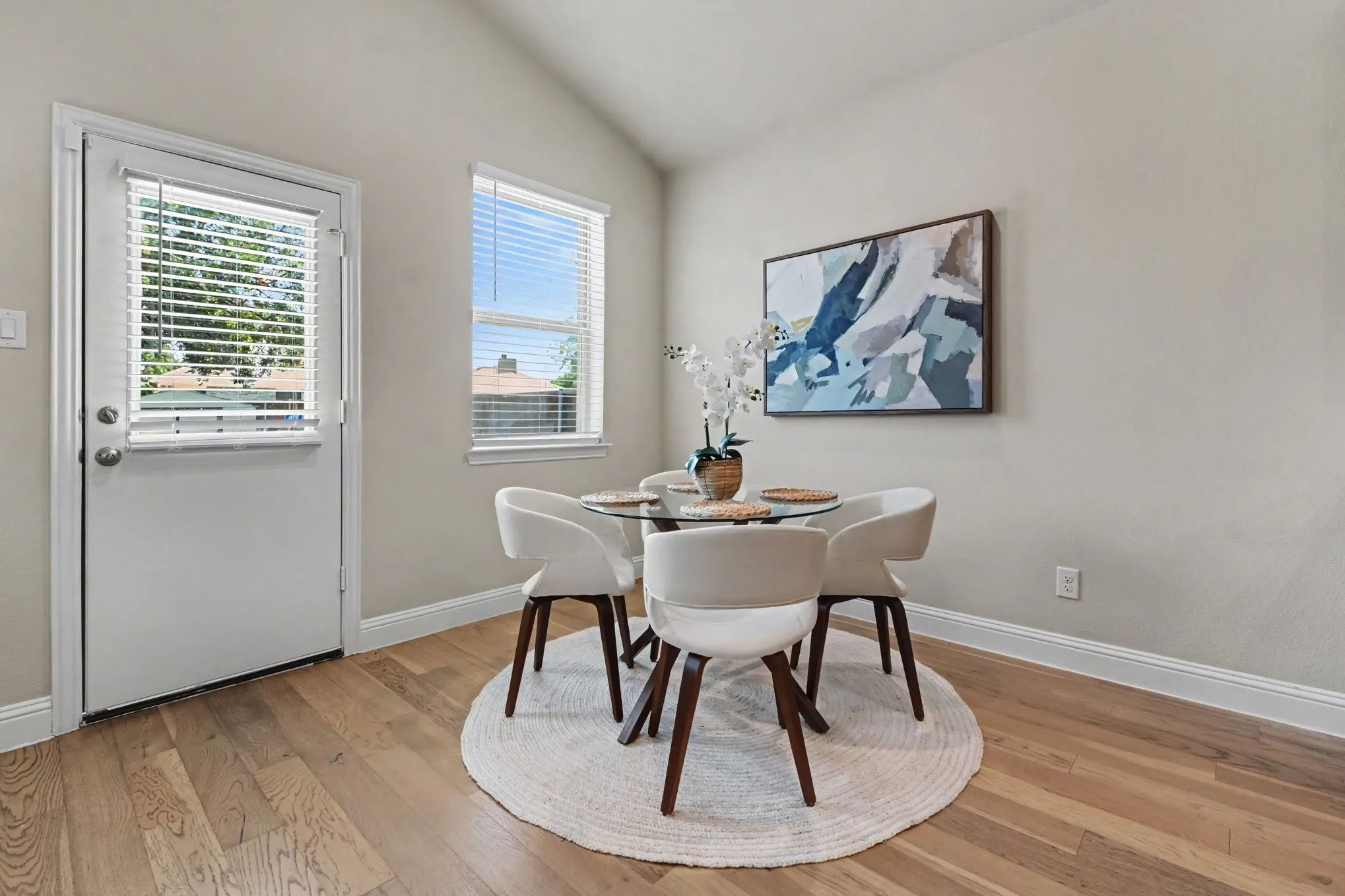 Vaulted ceiling with a white painted finish, wood-finish flooring, and white baseboards