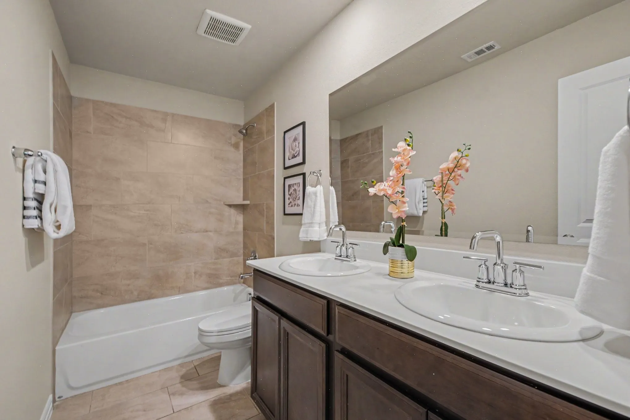 Dual vanity with integrated sinks, chrome fixtures, and dark wood-finish cabinetry