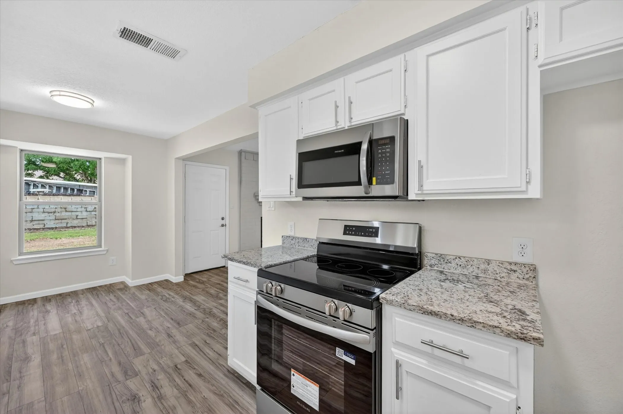 Contemporary kitchen featuring white cabinetry, stainless steel appliances, and granite countertops