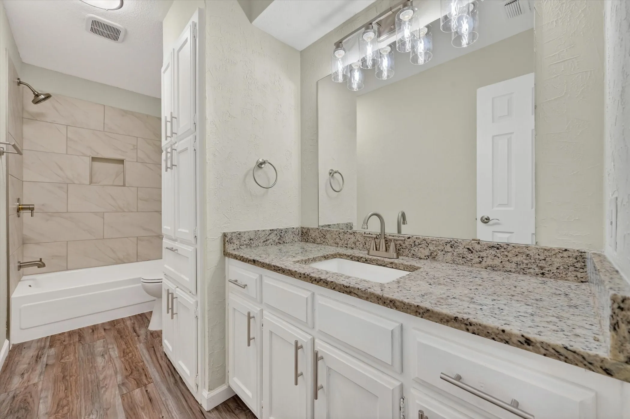 Bathroom featuring a white vanity with a granite-style countertop, undermount sink, and brushed nickel faucet