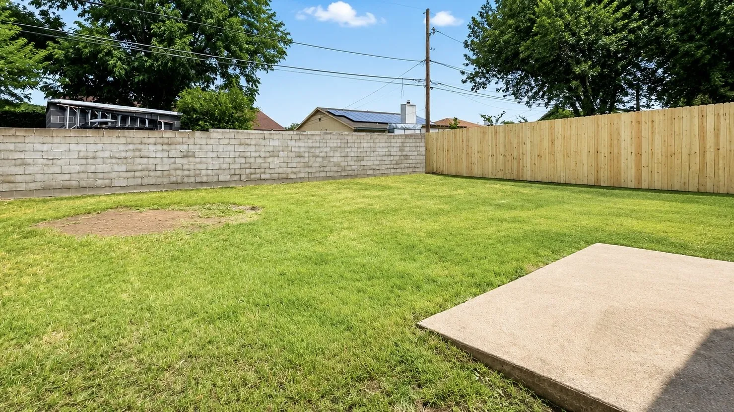 Expansive backyard featuring a concrete patio, a privacy fence, and a concrete block wall